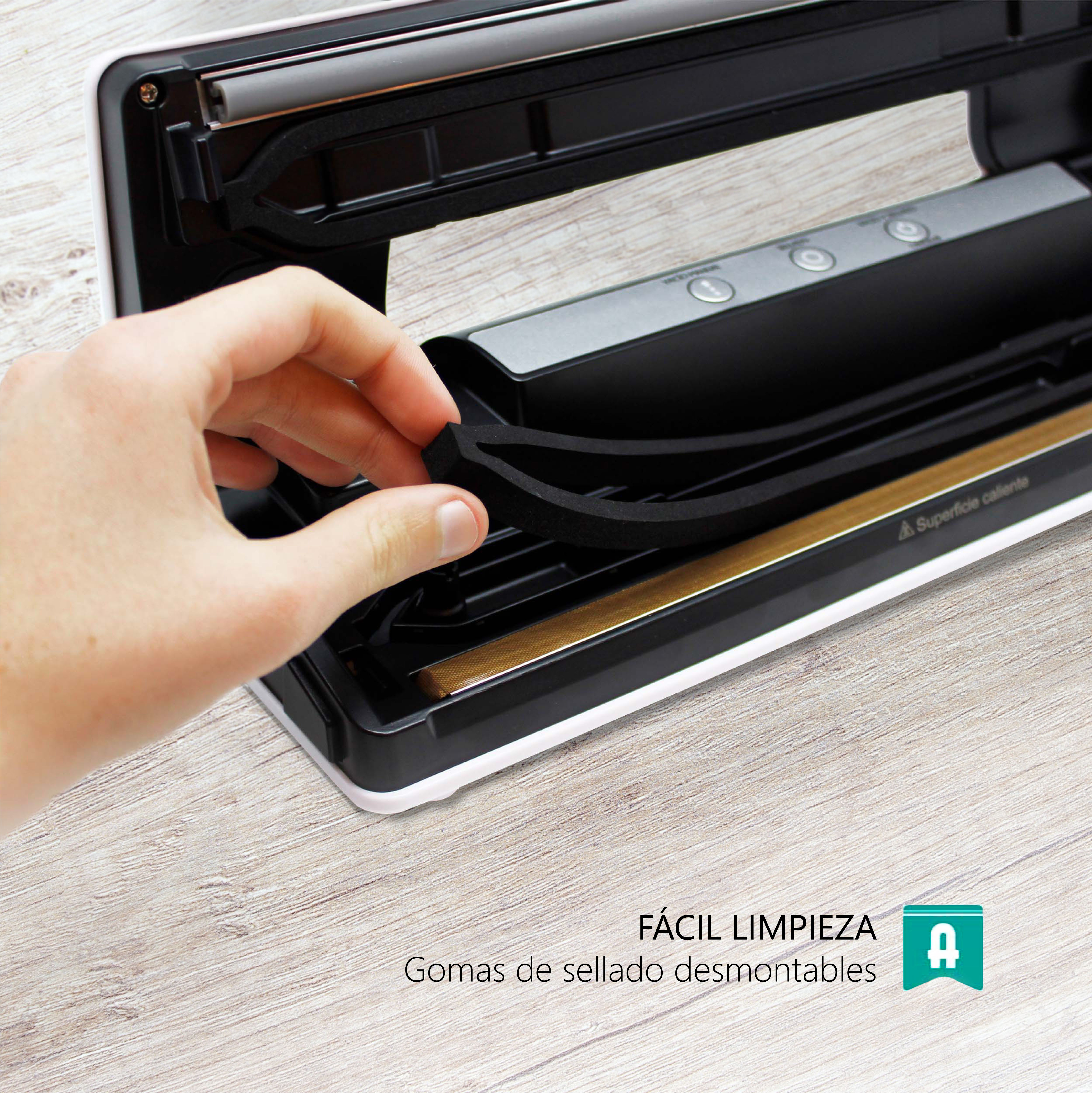 Mano quitando un sello de espuma de una envasadora al vacío negra. Texto "FÁCIL LIMPIEZA". Fondo de madera.