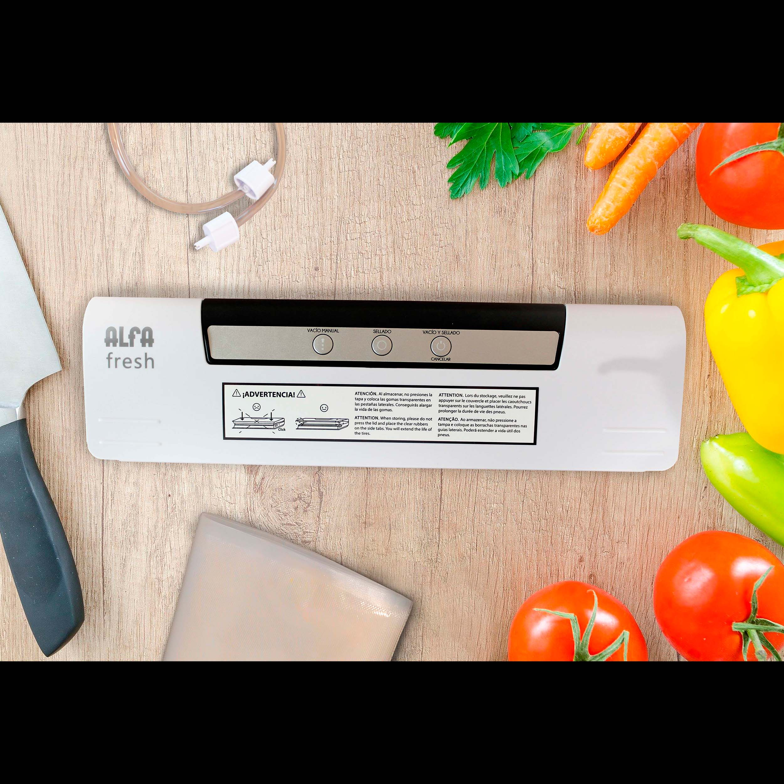 Una envasadora al vacío Alfa Fresh blanca con alimentos y verduras sobre madera. Cuchillo a la izquierda.