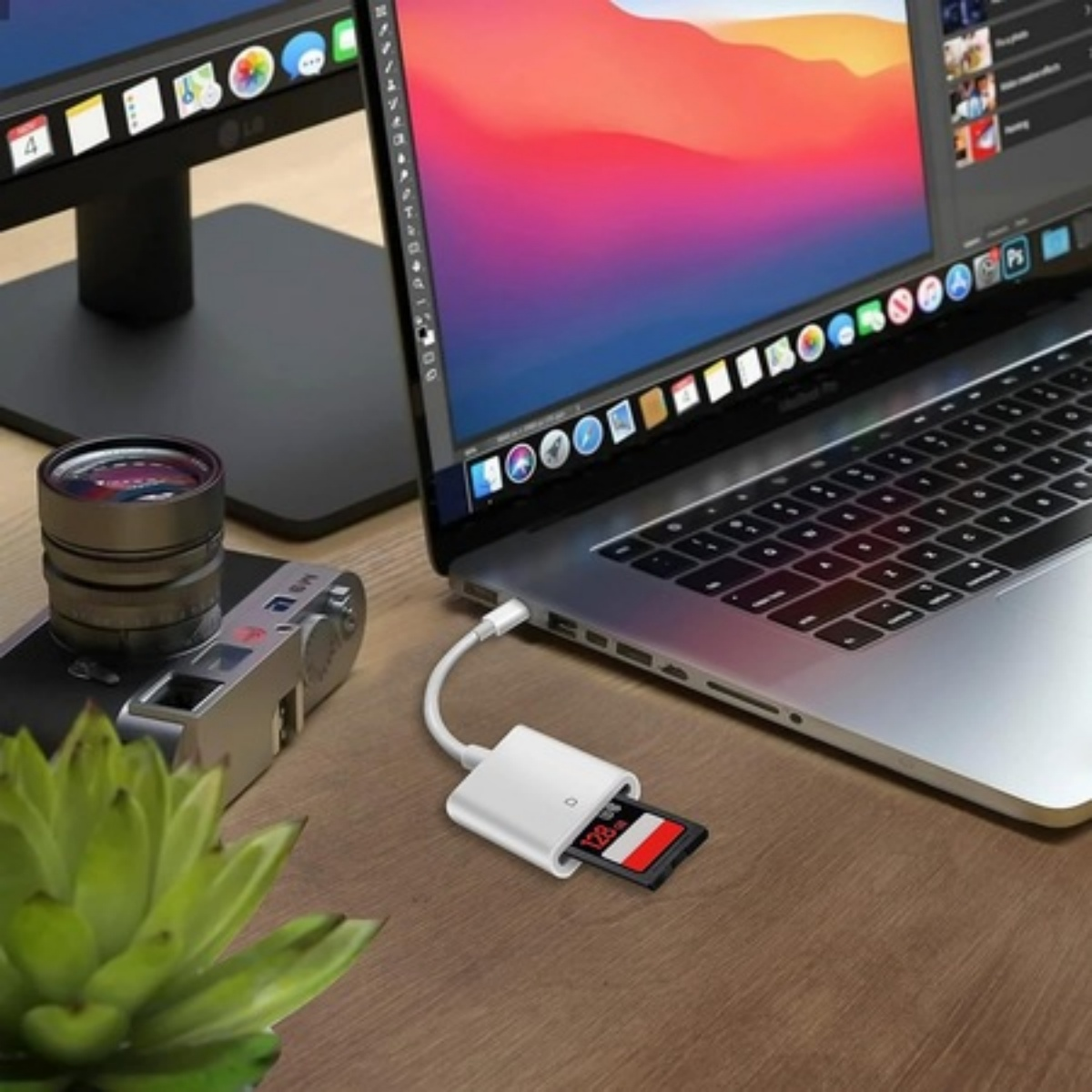 Ein Laptop mit angeschlossenem SD-Kartenleser. Eine Kamera und eine Pflanze stehen auf dem Tisch.