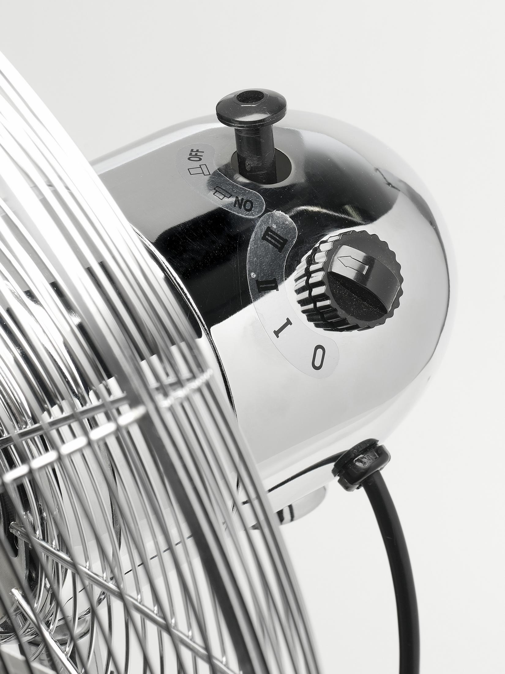 Primo piano del pannello di controllo di un ventilatore cromato. Il quadrante indica 'I', '0' e 'NO' con un interruttore on/off.