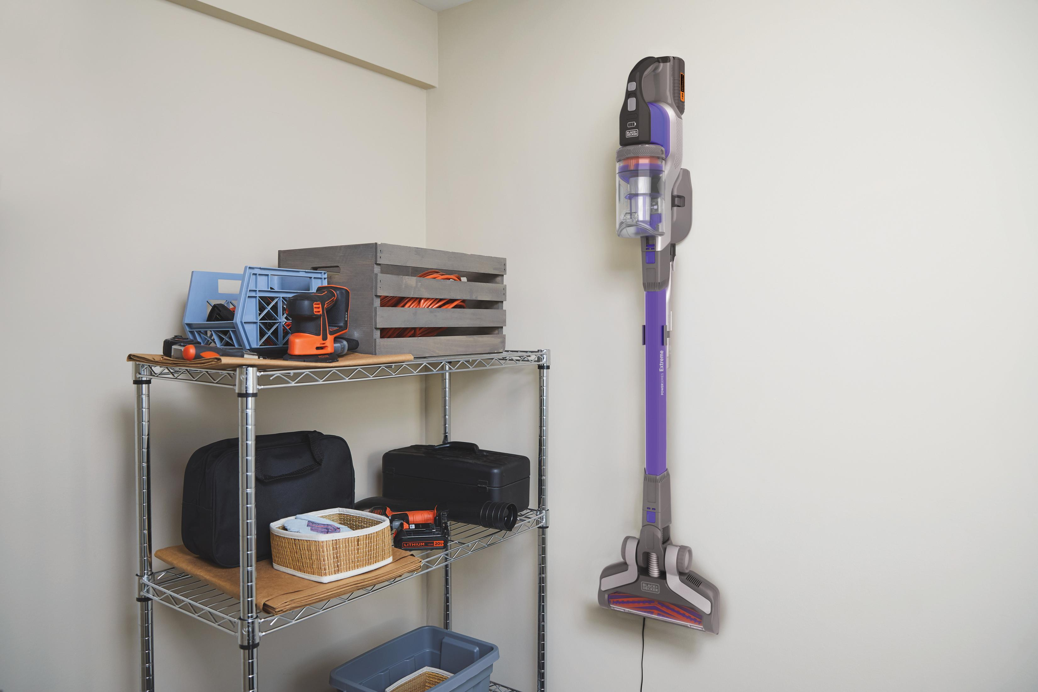 Vacuum cleaner and storage shelf with tools, boxes, and baskets in a well-lit room.