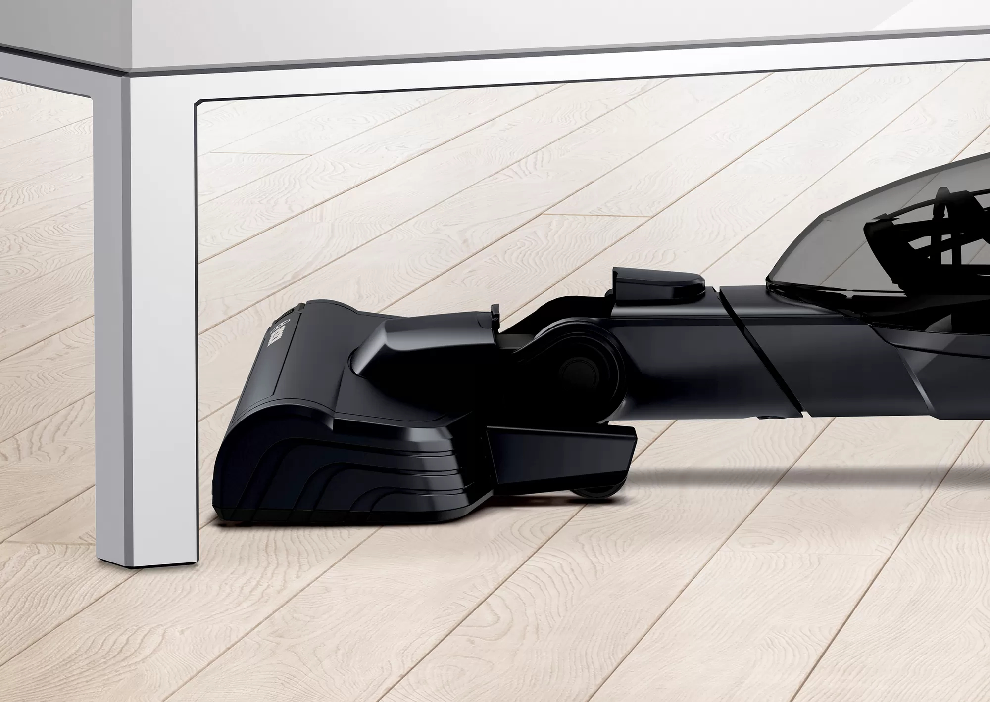 Czarna dysza odkurzacza czyszcząca pod białym stołem.