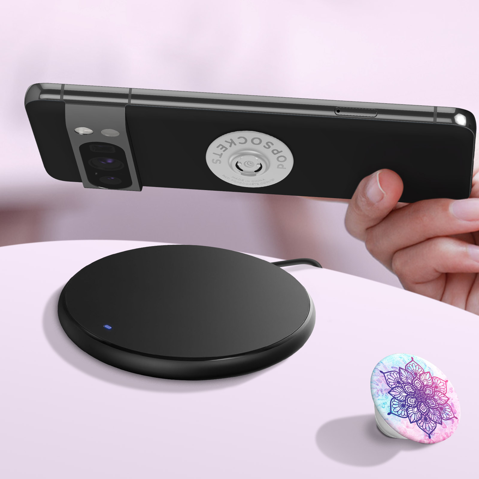 Un teléfono negro con un Popsocket en un cargador inalámbrico. Otro Popsocket a la derecha.