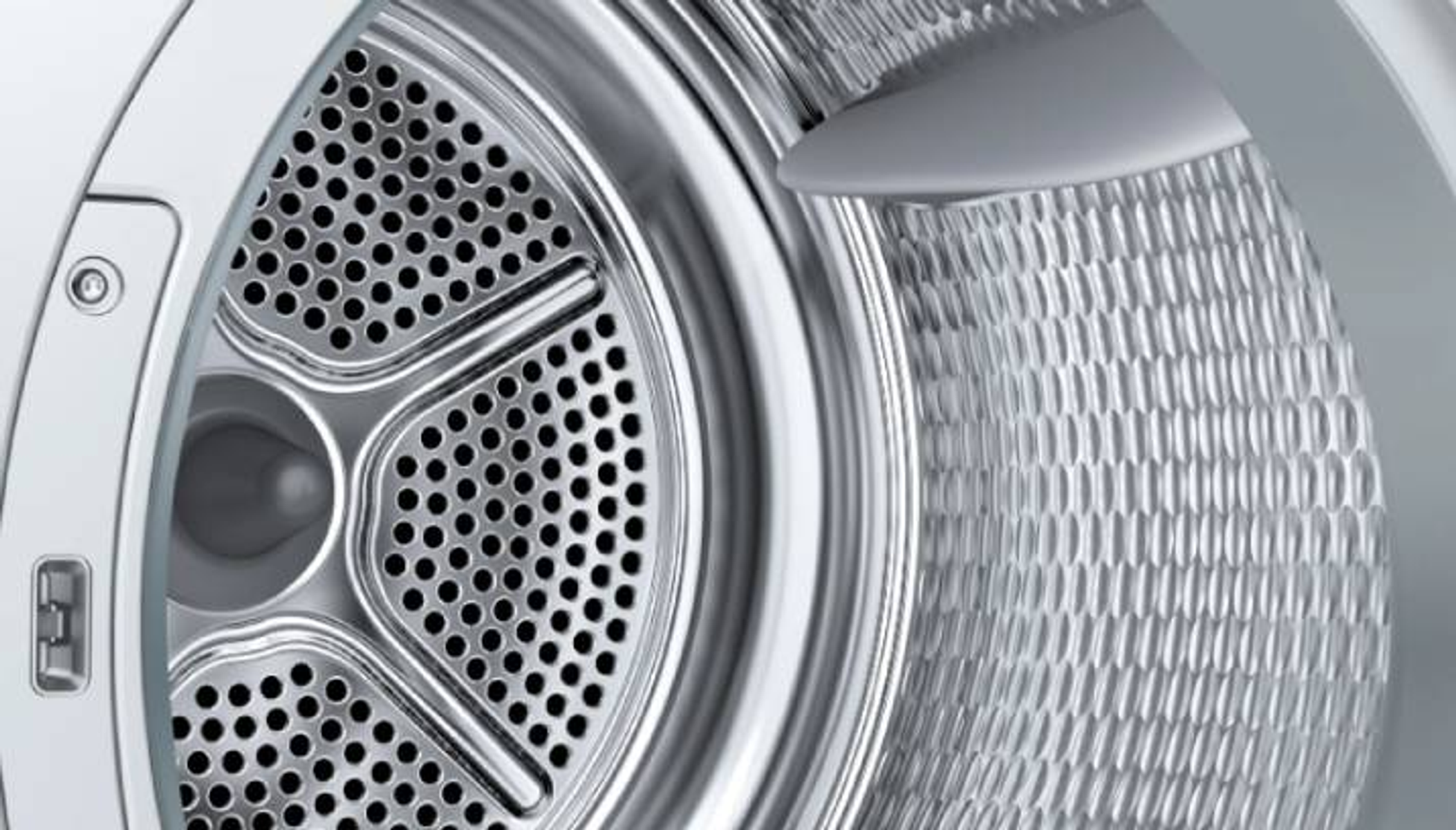 Interno del cestello della lavatrice in acciaio inox, con fori. Primo piano.
