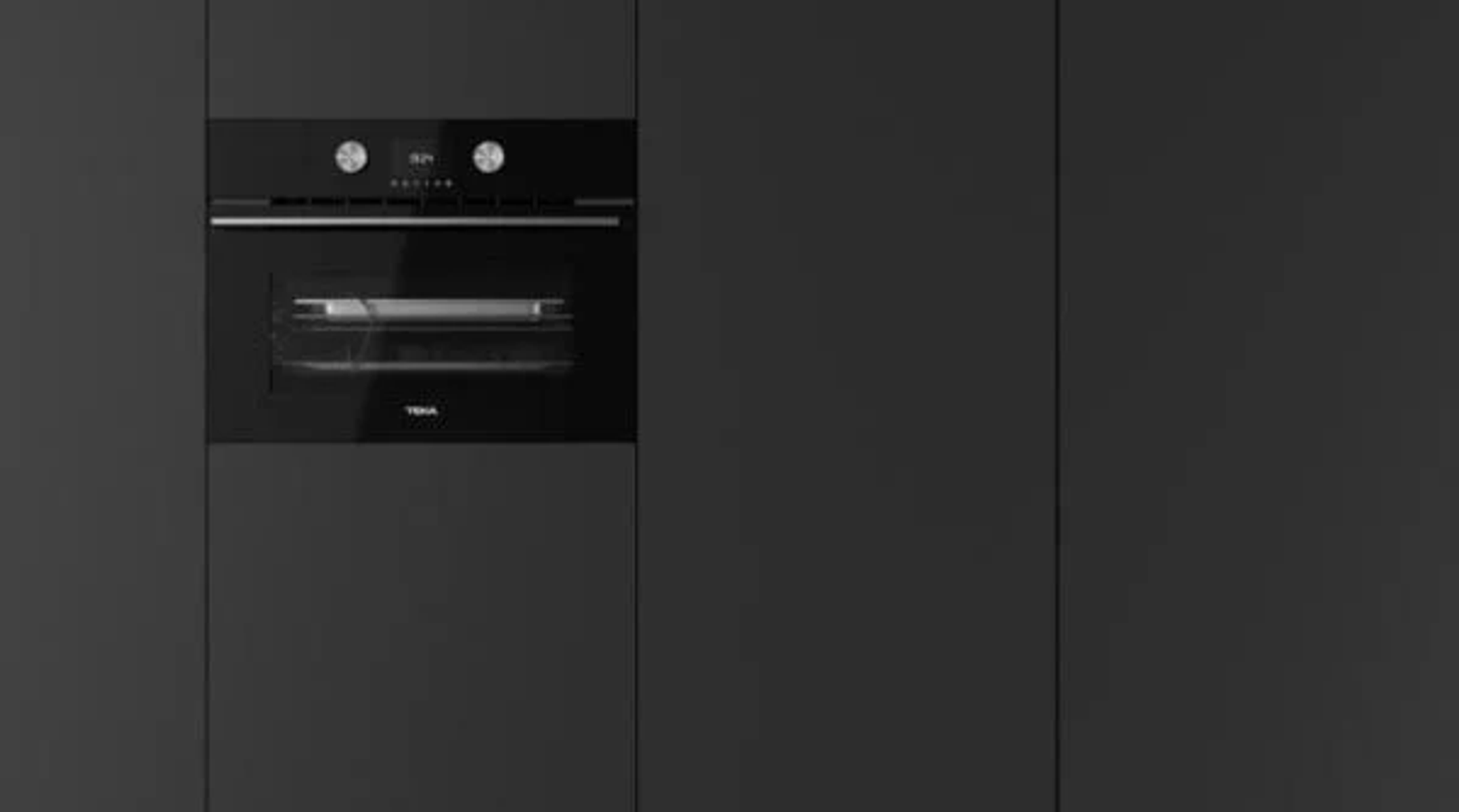 Horno negro empotrado en armario gris oscuro. Puerta cerrada, con logotipo Teka.