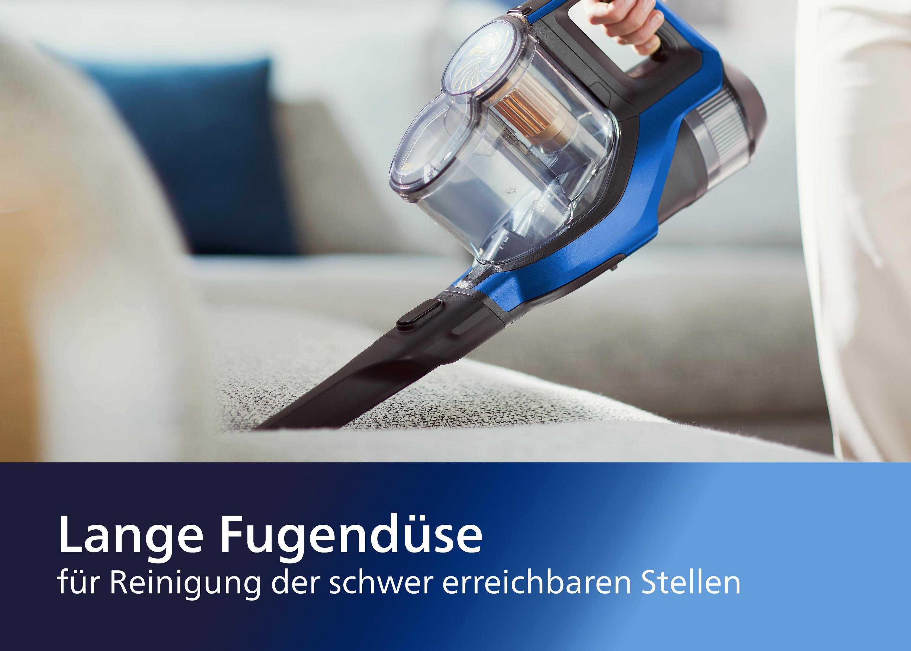 Odkurzacz ręczny usuwający zanieczyszczenia z sofy. Odkurzacz jest niebiesko-czarny.