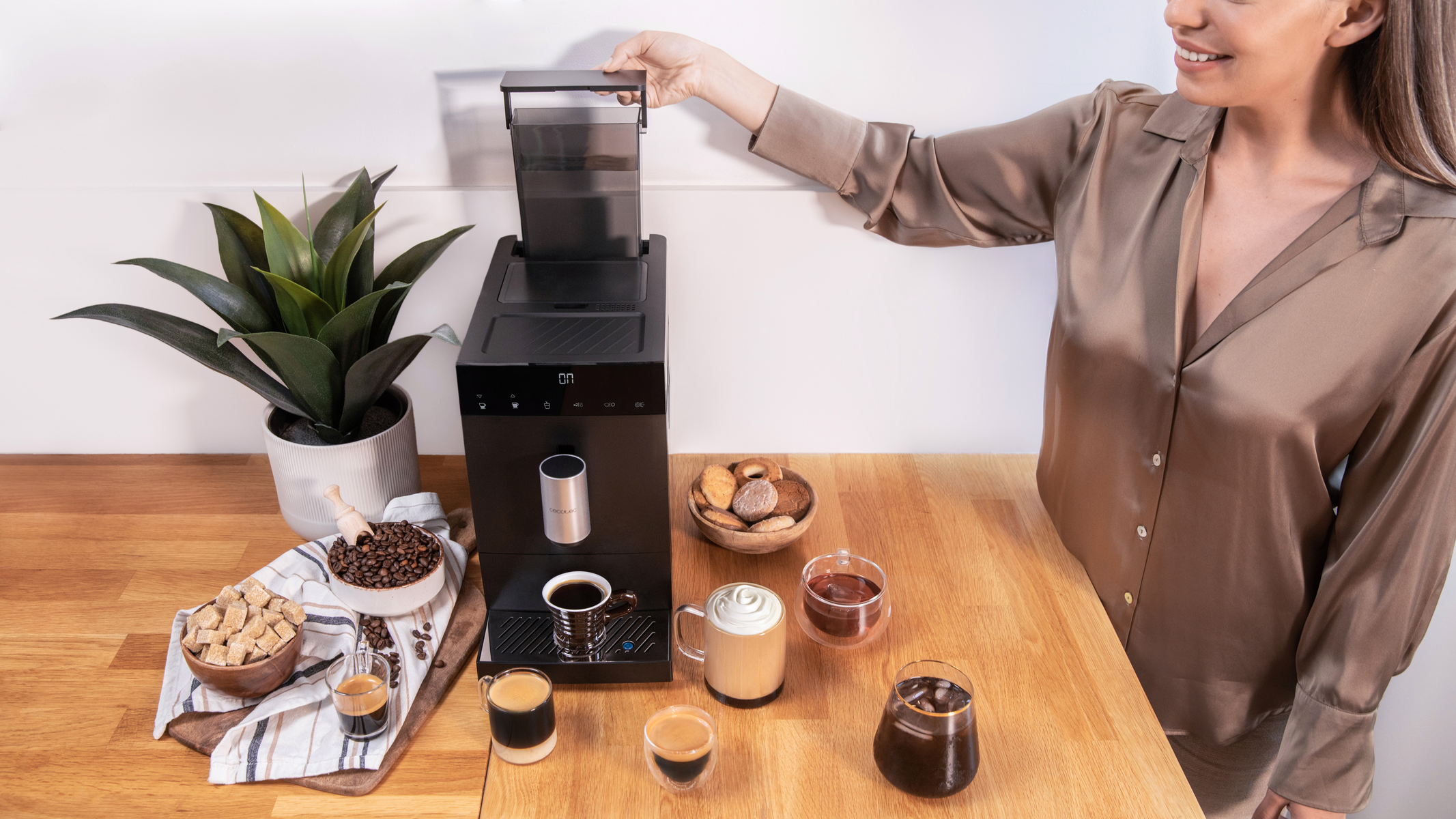 Kobieta otwiera ekspres do kawy. Kawa i ciastka są na stole.