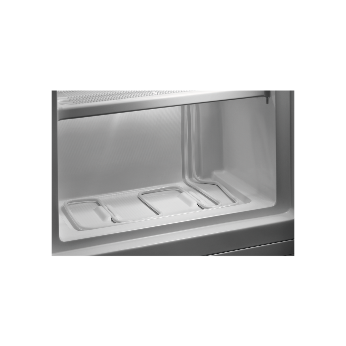Interior de un refrigerador blanco, mostrando estantes y elementos de enfriamiento.