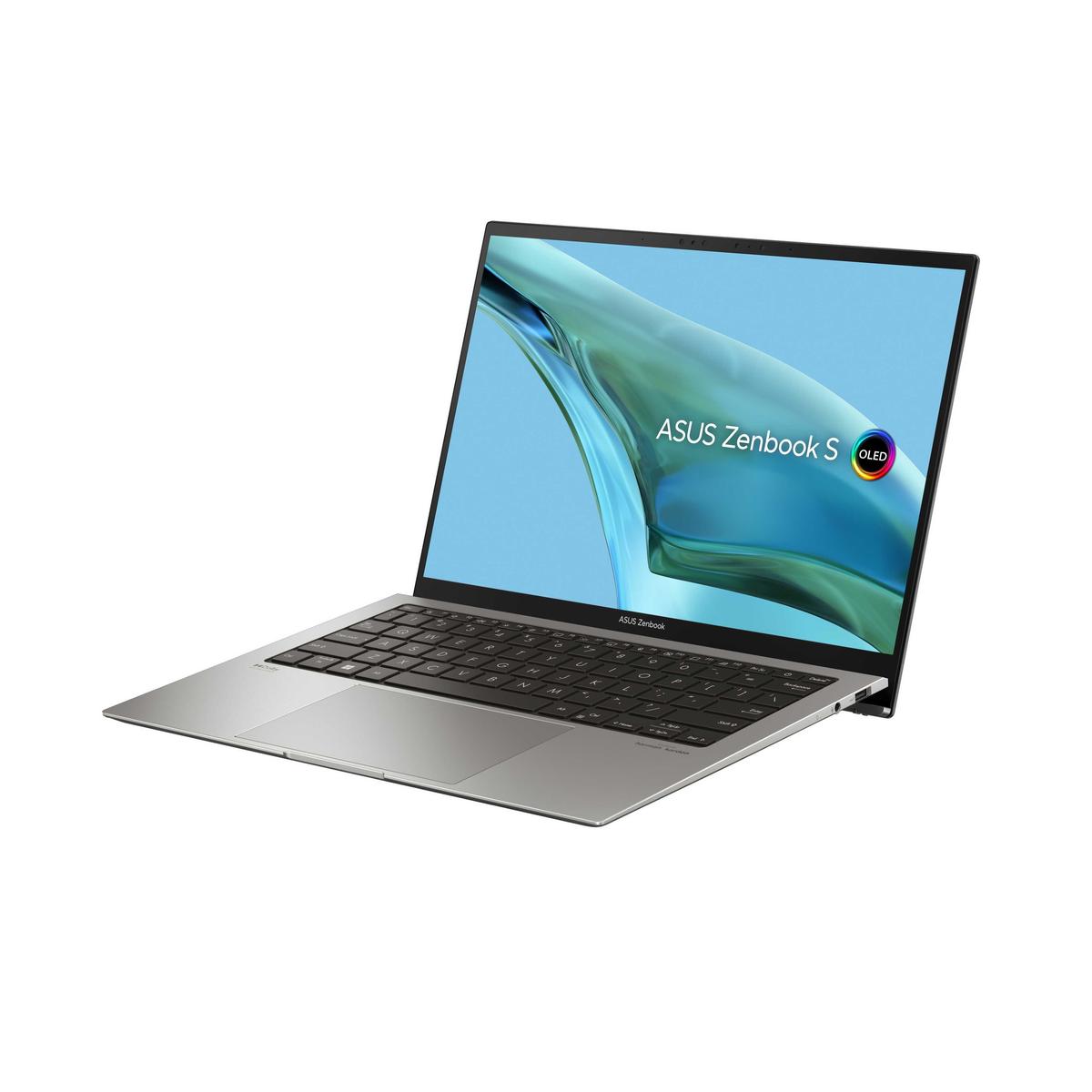 Laptop plateado, ligeramente abierto, sobre superficie blanca. Pantalla: 'ASUS Zenbook S'.