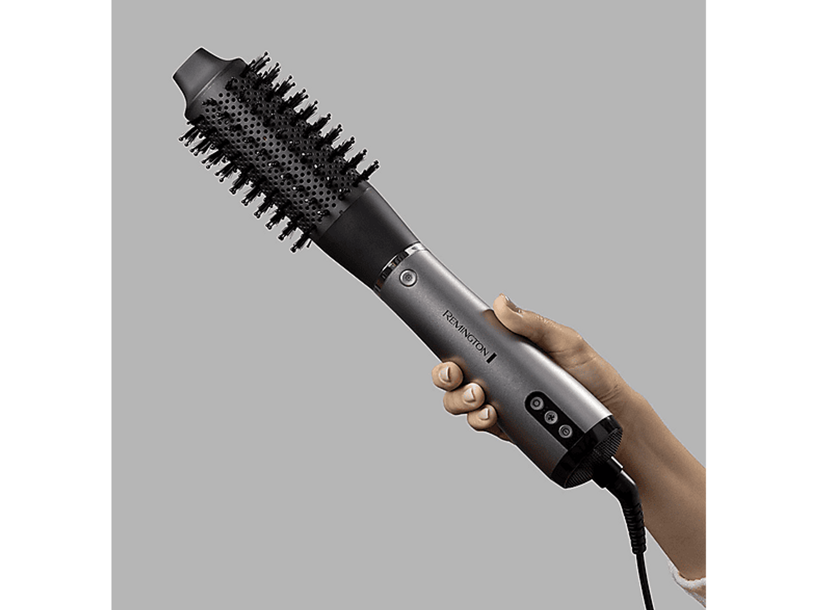 Mano che tiene un Remington per capelli argento e nero con testina a spazzola.