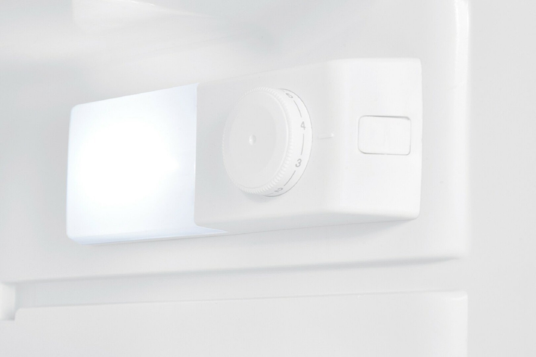 Intérieur d'un réfrigérateur blanc avec une lumière et un cadran de contrôle de la température.