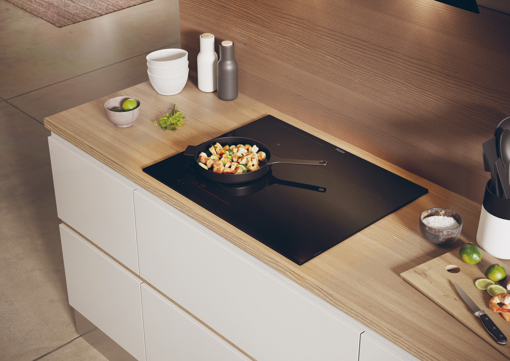 Scena kuchenna z czarną płytą indukcyjną z gotującym się jedzeniem i różnymi przyborami kuchennymi.