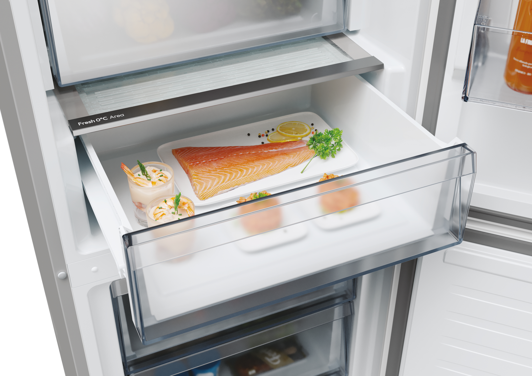 Cassetto frigorifero con salmone, gamberi e limone. Il cassetto è aperto in un frigorifero bianco.