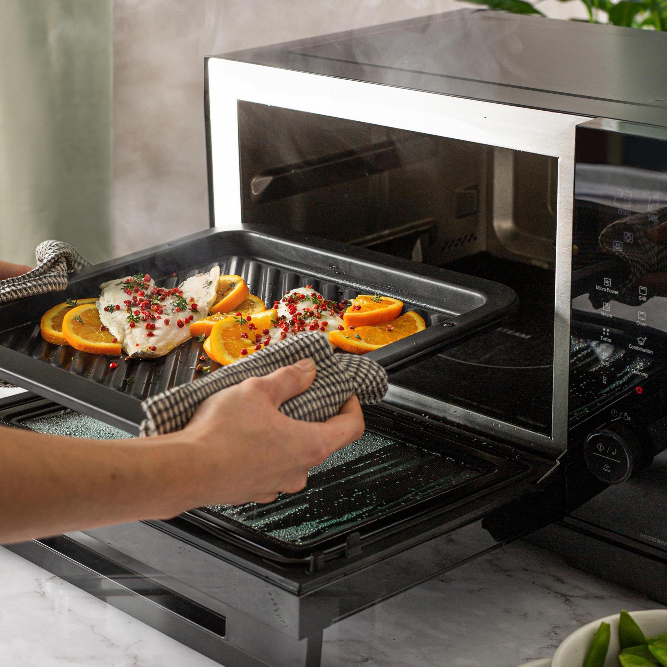 Cibo rimosso dal forno a microonde. Fette d'arancia e cibo.