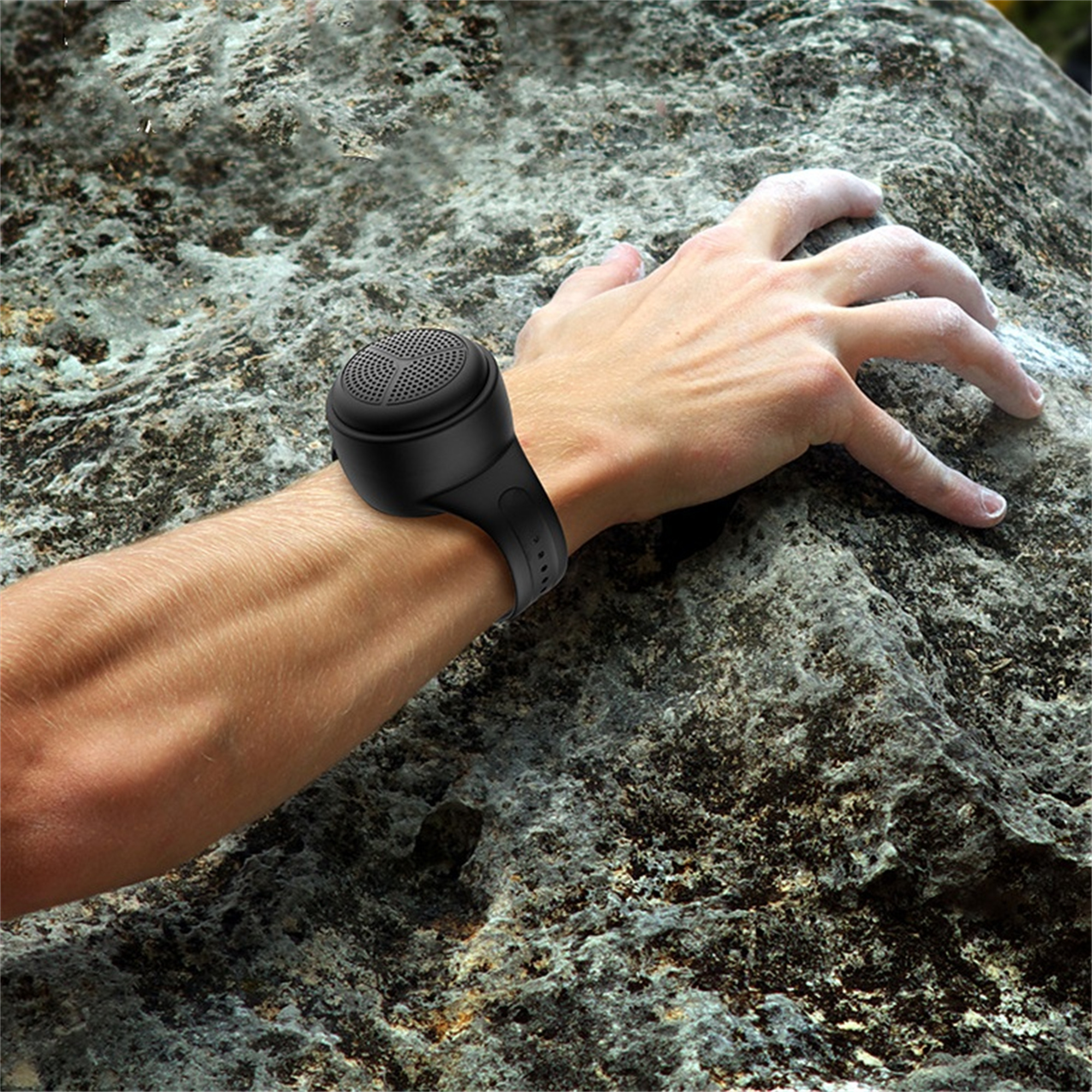Ein Arm mit einer schwarzen Lautsprecheruhr auf einem Felsen.