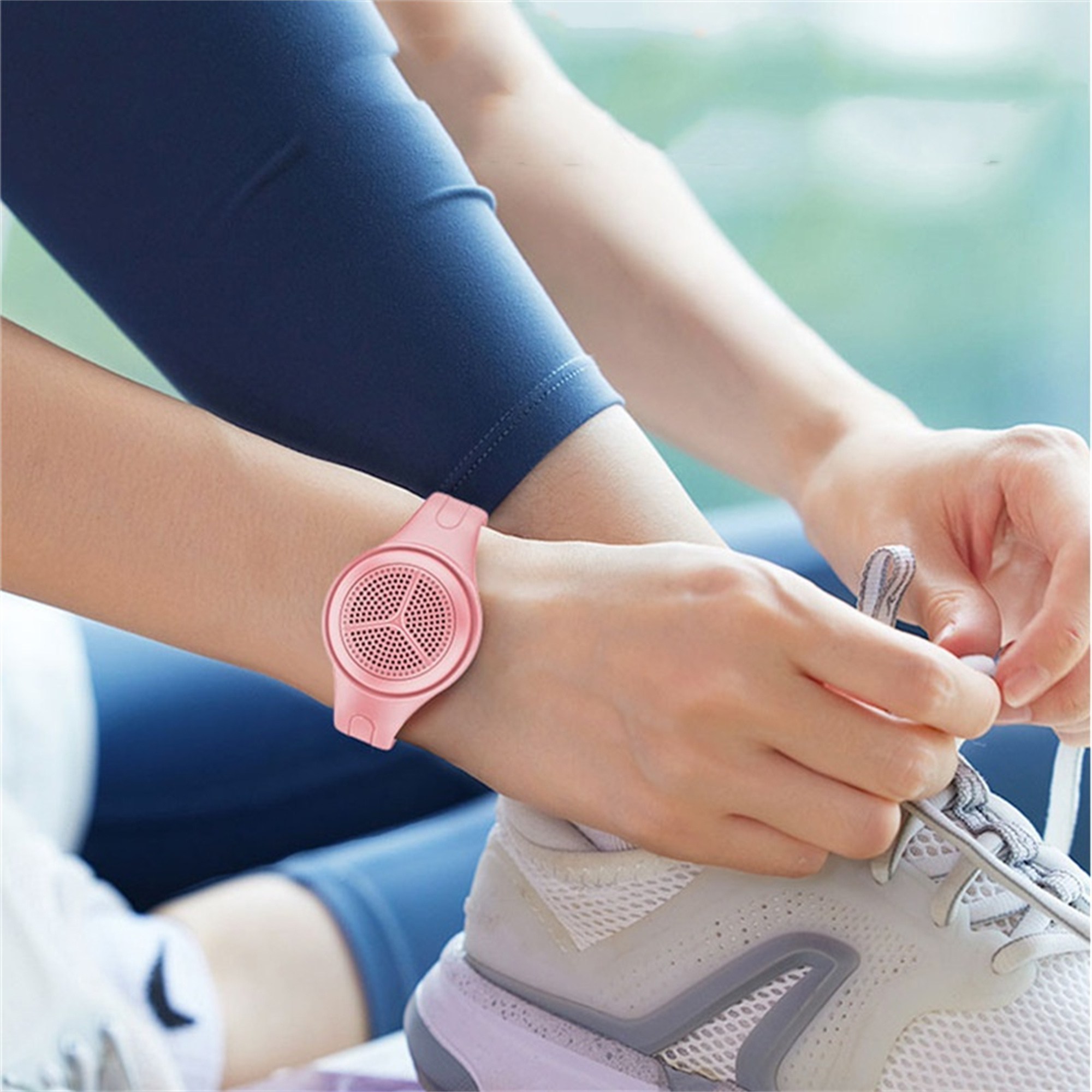 Eine rosa Smartwatch am Handgelenk. Eine Person bindet einen Schuh, trägt Leggings und einen Schuh.