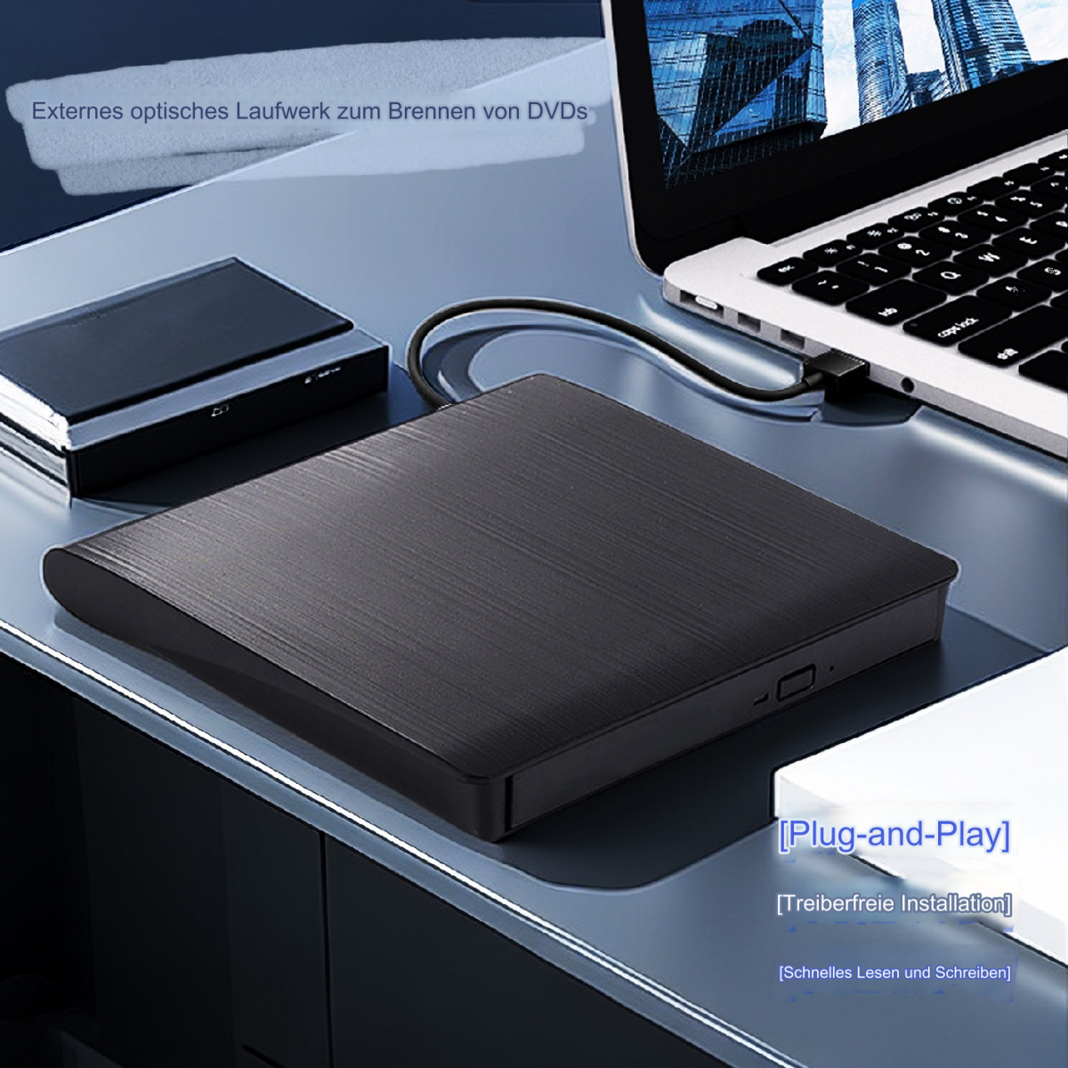 Schwarzes externes DVD-Laufwerk, an einen Laptop angeschlossen, auf blauer Oberfläche.