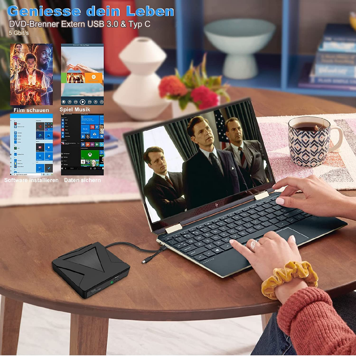 Ein Laptop offen auf einem Tisch, mit einem schwarzen DVD-Brenner und den Händen einer Frau.