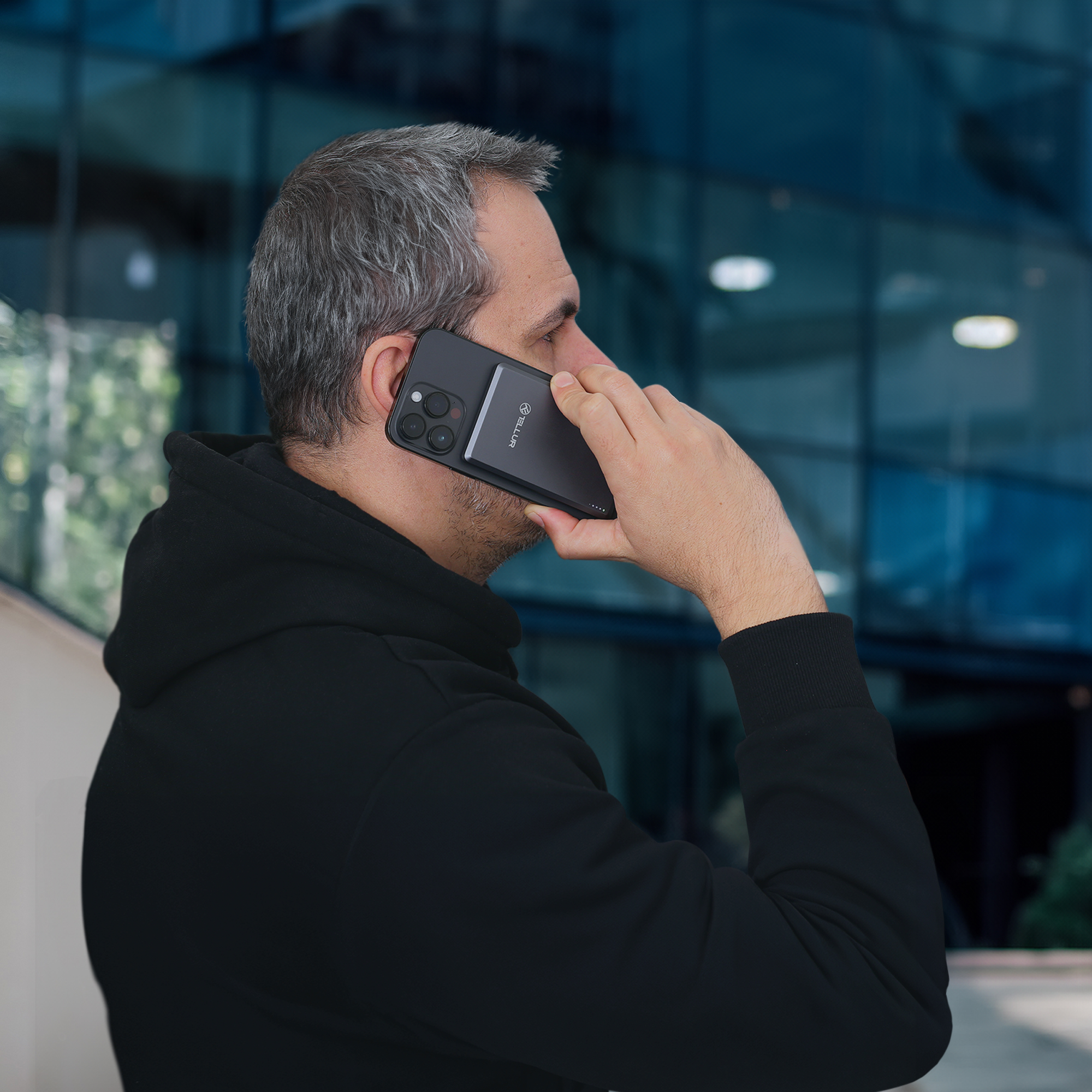 Mężczyzna trzymający telefon przy uchu. Stoi przed budynkiem.