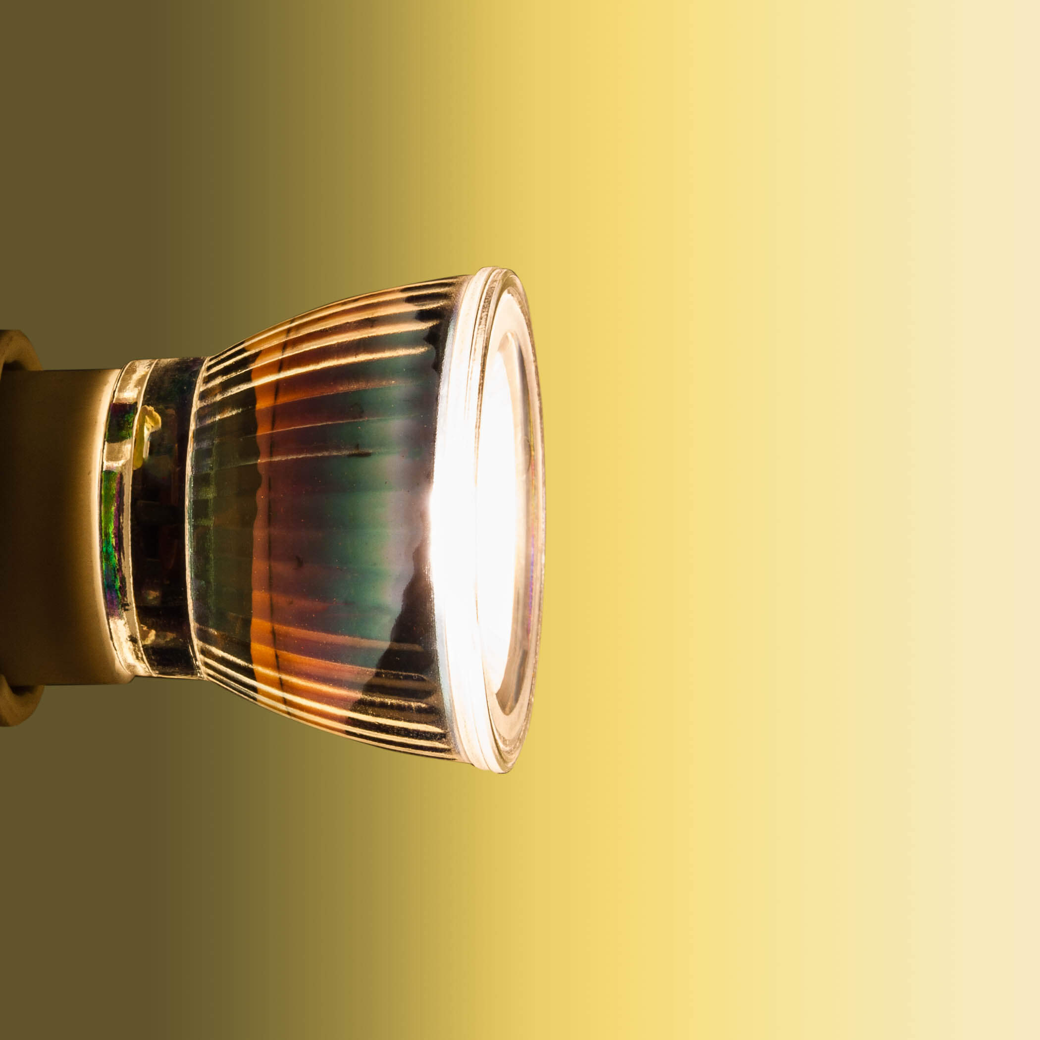 Primo piano di una lampadina che emette una luce intensa. Lo sfondo ha una sfumatura gialla.