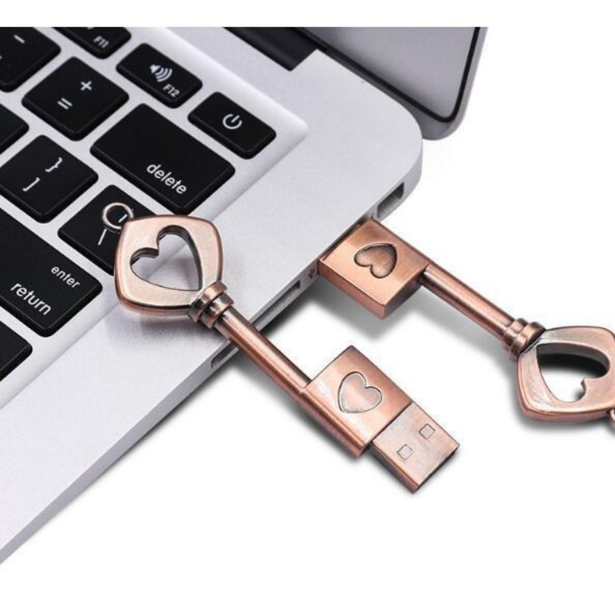 Zwei USB-Schlüssel in Form von Schlüsseln mit Herzdetails sind an einen Laptop angeschlossen.