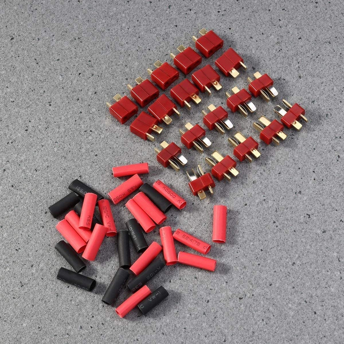 Rote und goldene Stecker und rot-schwarze Schrumpfschläuche. Auf hellgrauer Oberfläche angeordnet.