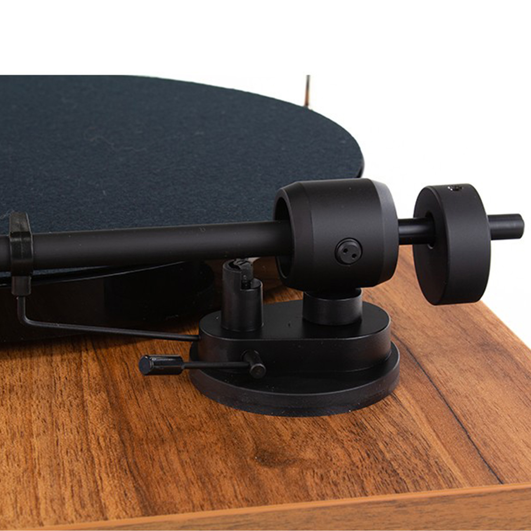 Zbliżenie czarnego ramienia i wkładki gramofonu na drewnianej podstawie, z czarną płytą.