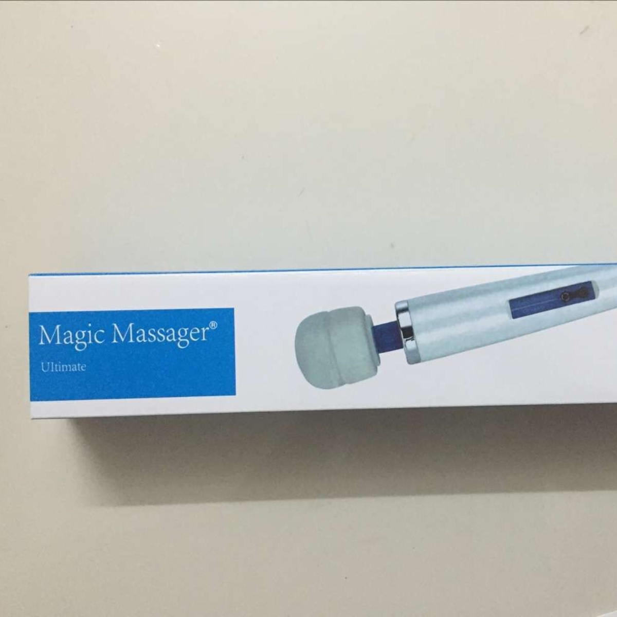 Eine Schachtel von Magic Massager Ultimate. Der Massager ist weiß, mit einer blauen Spitze.