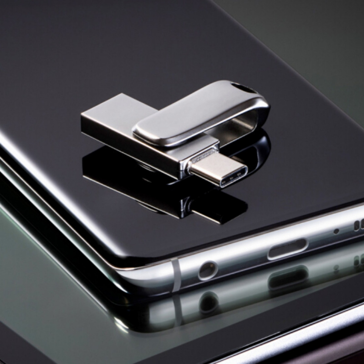 Silberner USB-C-Stick auf einem schwarzen Telefon. Der Stick ist in das Telefon eingesteckt.