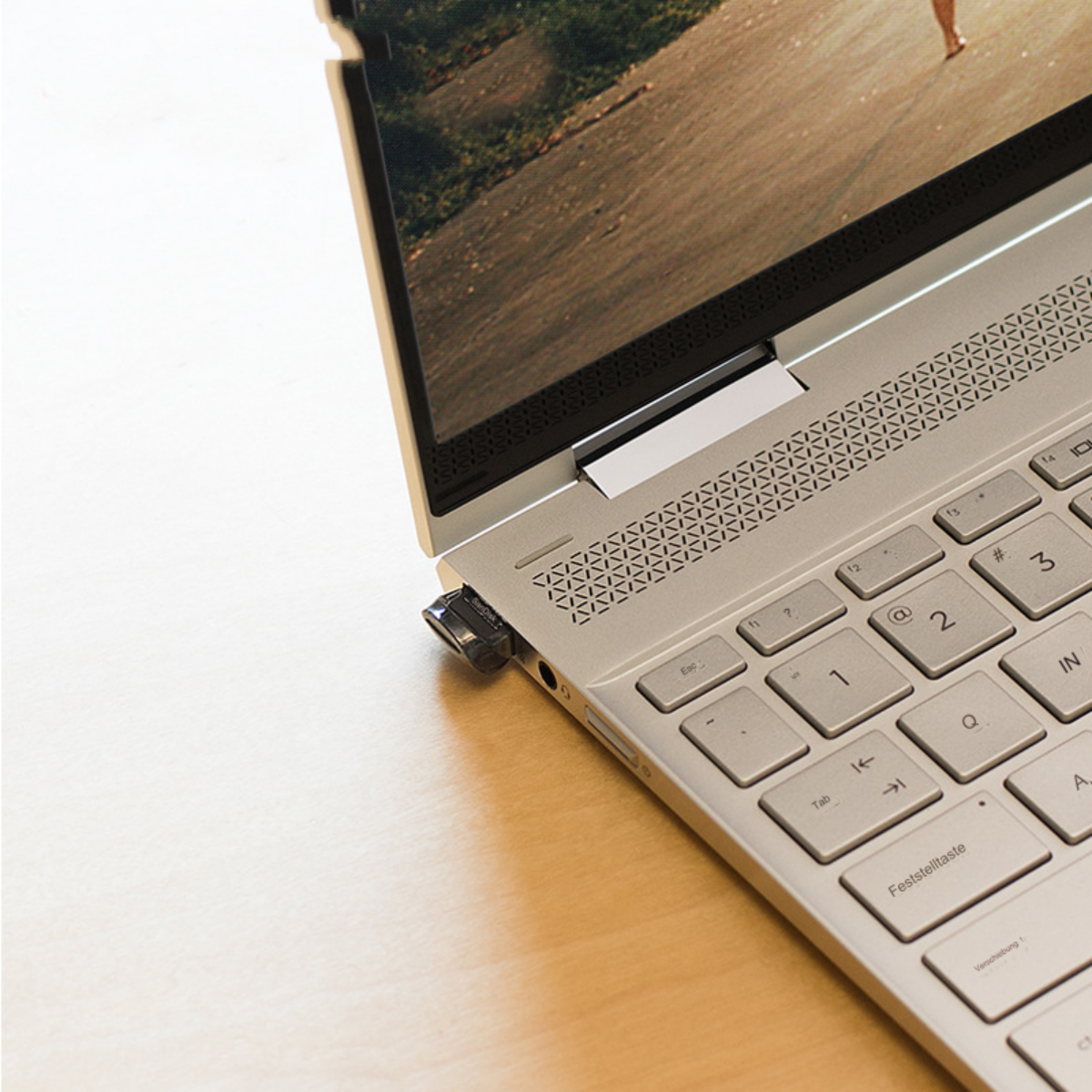 Laptop mit eingestecktem USB-Stick, zeigt eine Person beim Gehen auf dem Bildschirm.