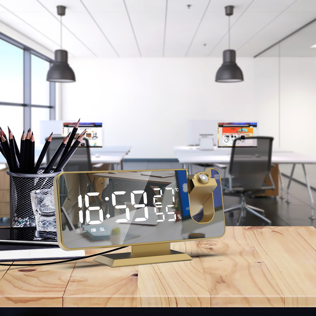 Goldene Digitaluhr mit Zeitanzeige, Schreibtisch und Bleistiften im Vordergrund.