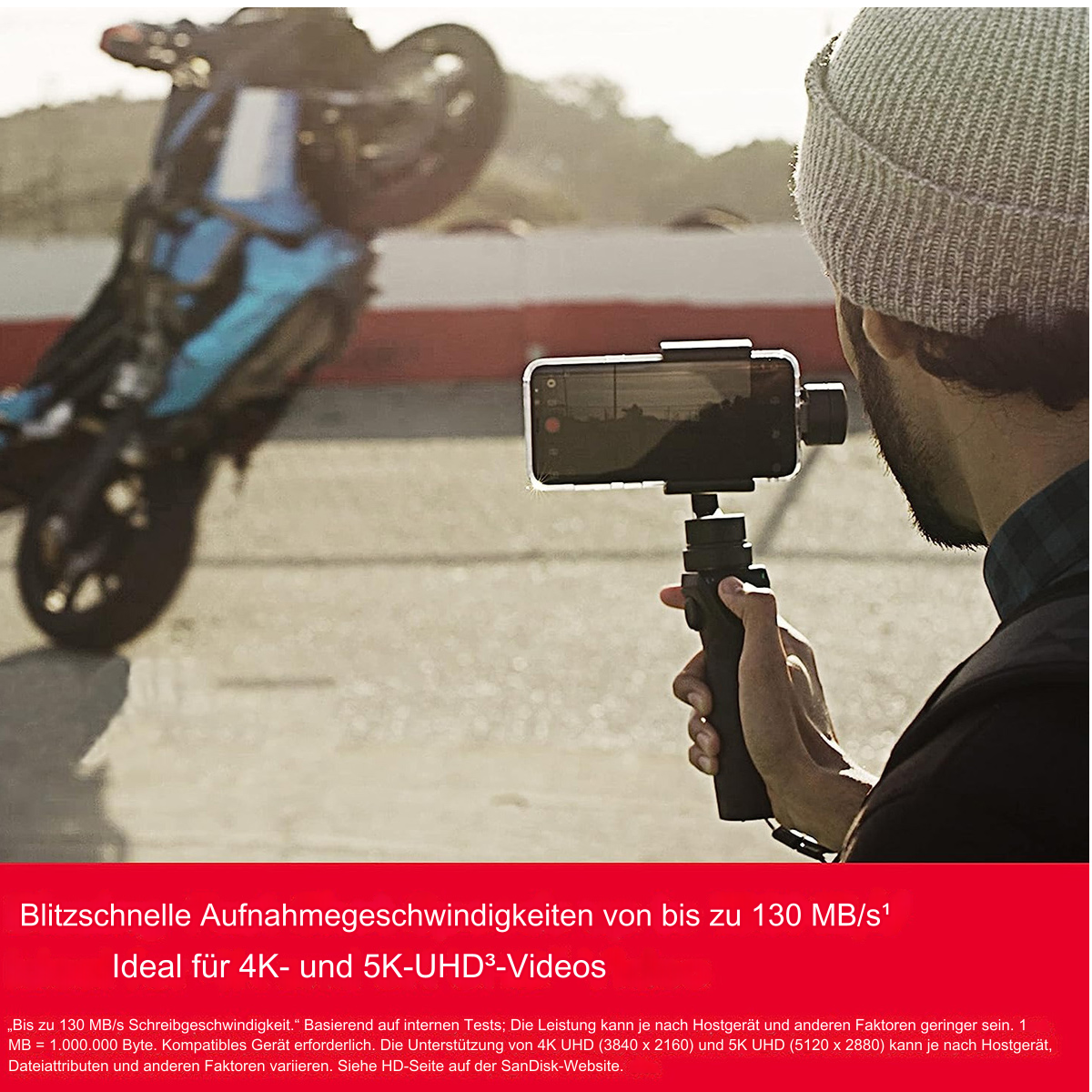Ein Mann hält ein Smartphone auf einem Gimbal und filmt ein Motorrad, das einen Wheelie macht.