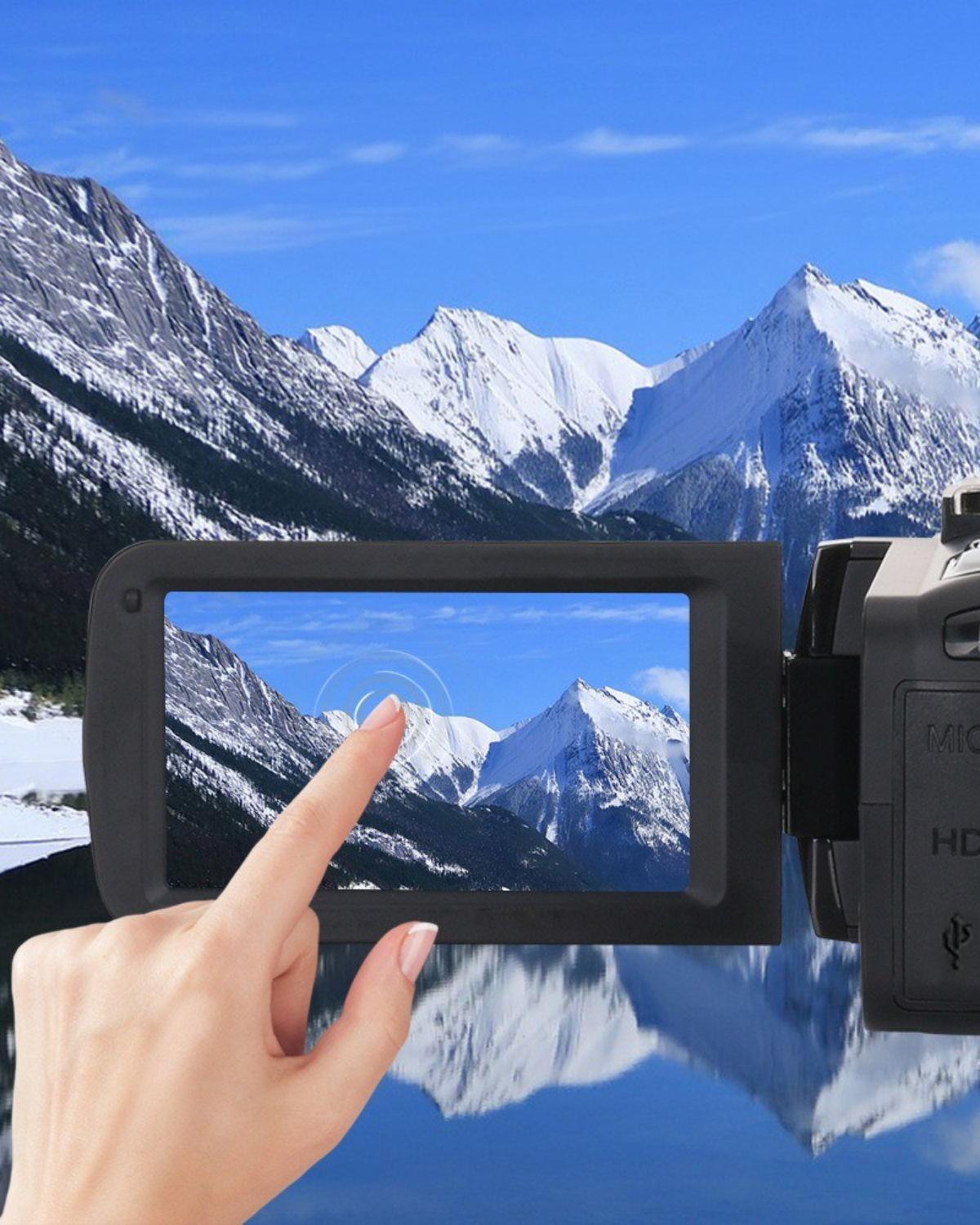 Hand berührt einen Videokamera-Bildschirm, der eine schneebedeckte Berglandschaft zeigt.