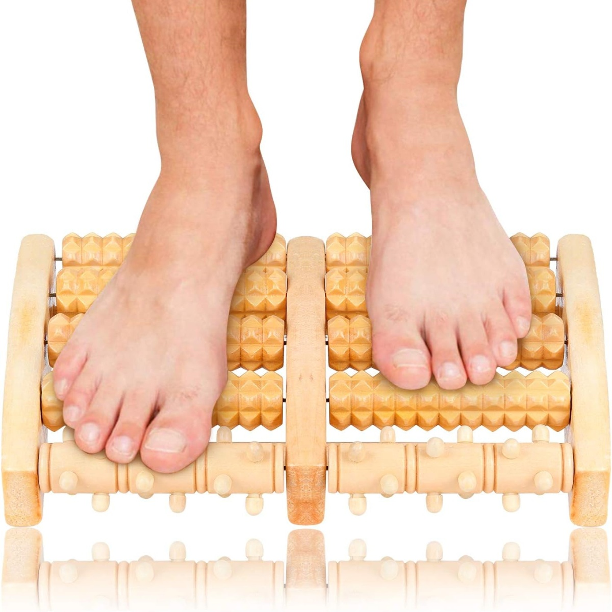 Füße auf einem Fußmassagegerät aus Holz, weißer Hintergrund.