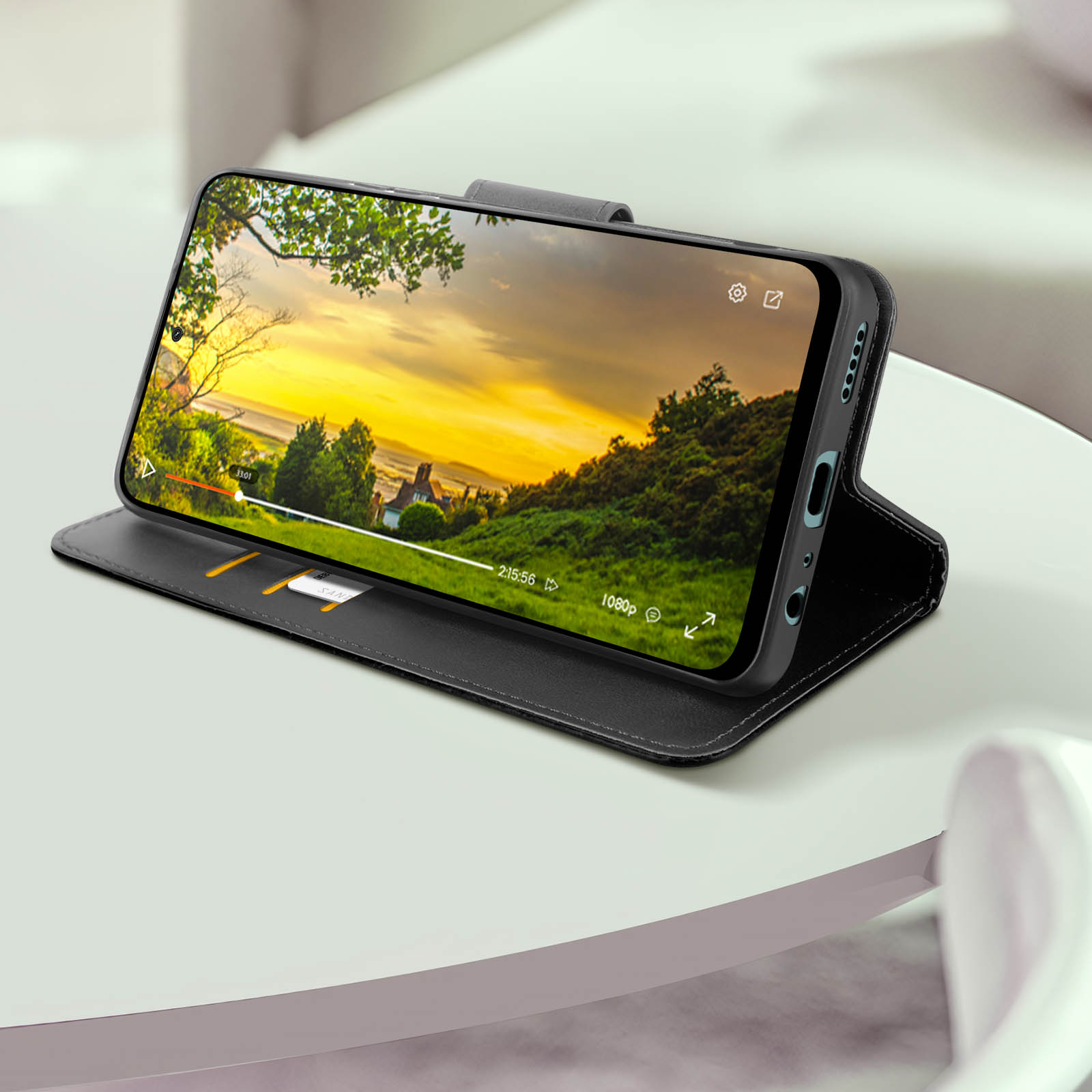 Smartphone in custodia nera con video. Custodia su tavolo bianco, sfondo sfocato.