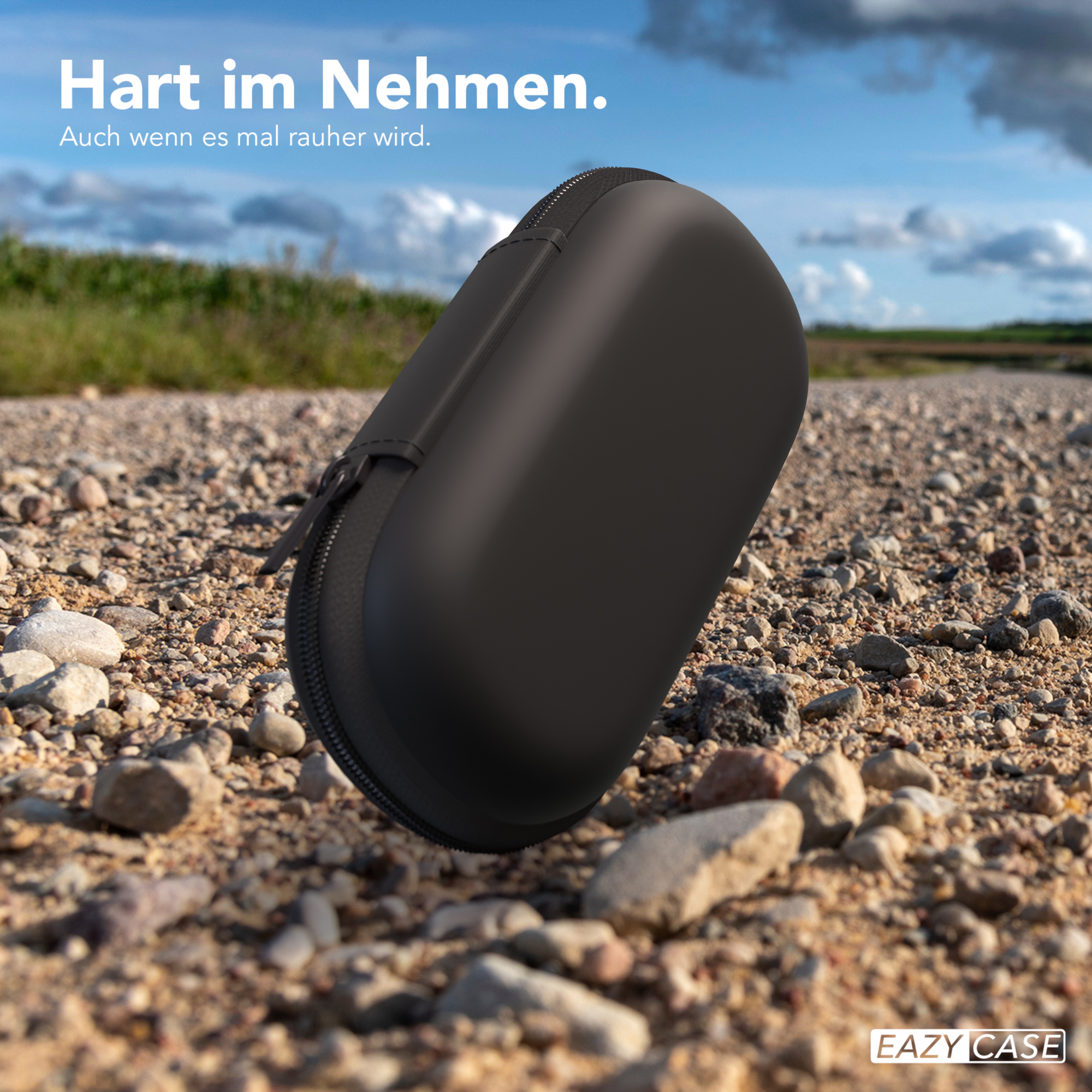 Schwarzes, ovales Etui mit Reißverschluss auf Schotterstraße, mit Text.