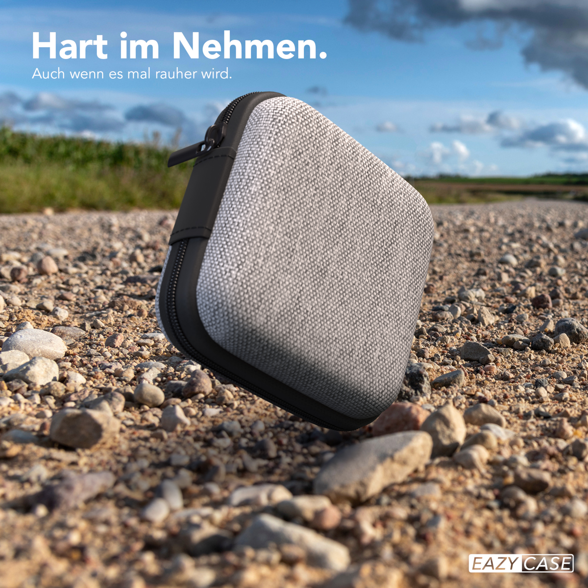 Graues Etui auf einer Schotterstraße mit Himmels Hintergrund.
