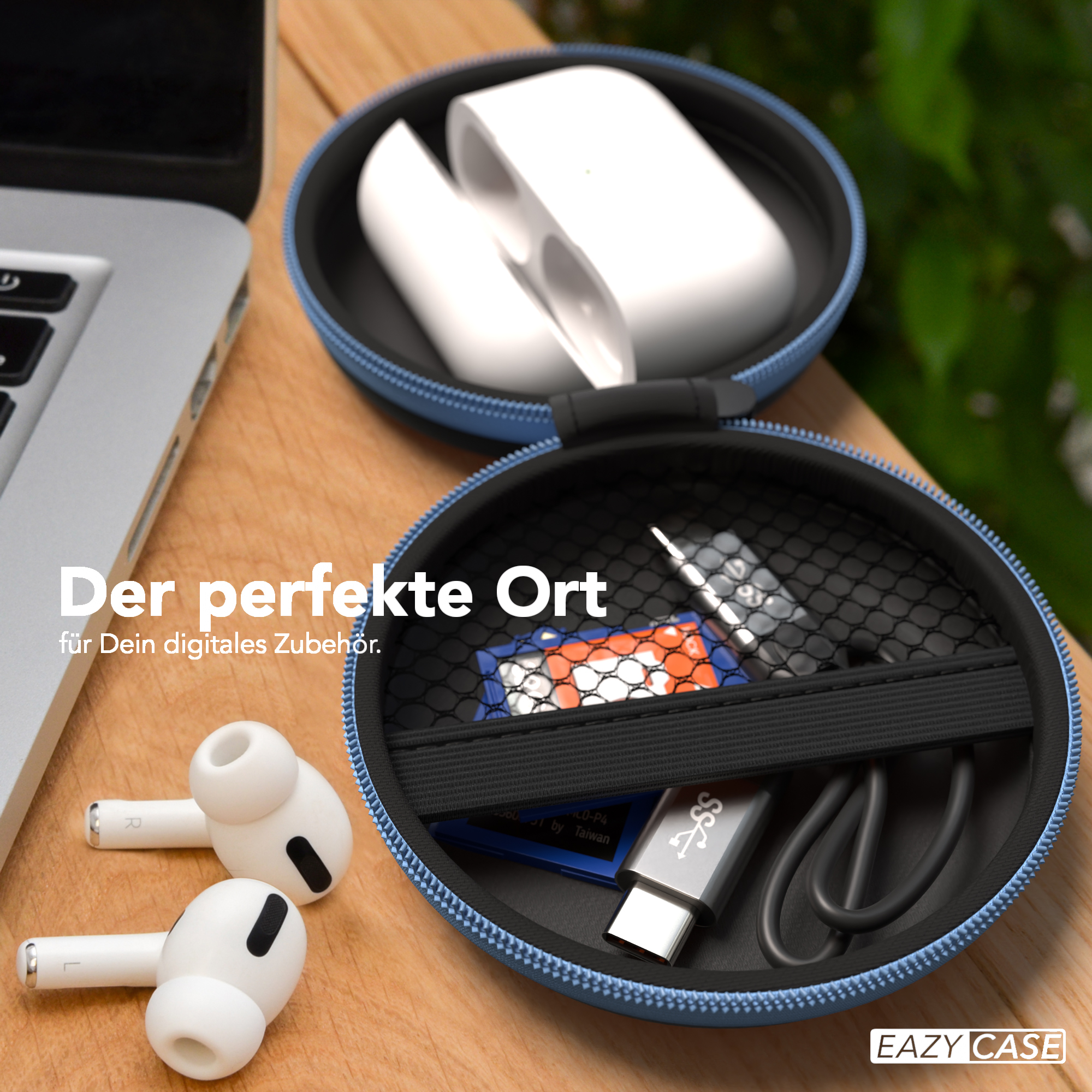 Offenes blaues Etui mit AirPods und Zubehör. Etui auf Holzoberfläche neben Laptop.