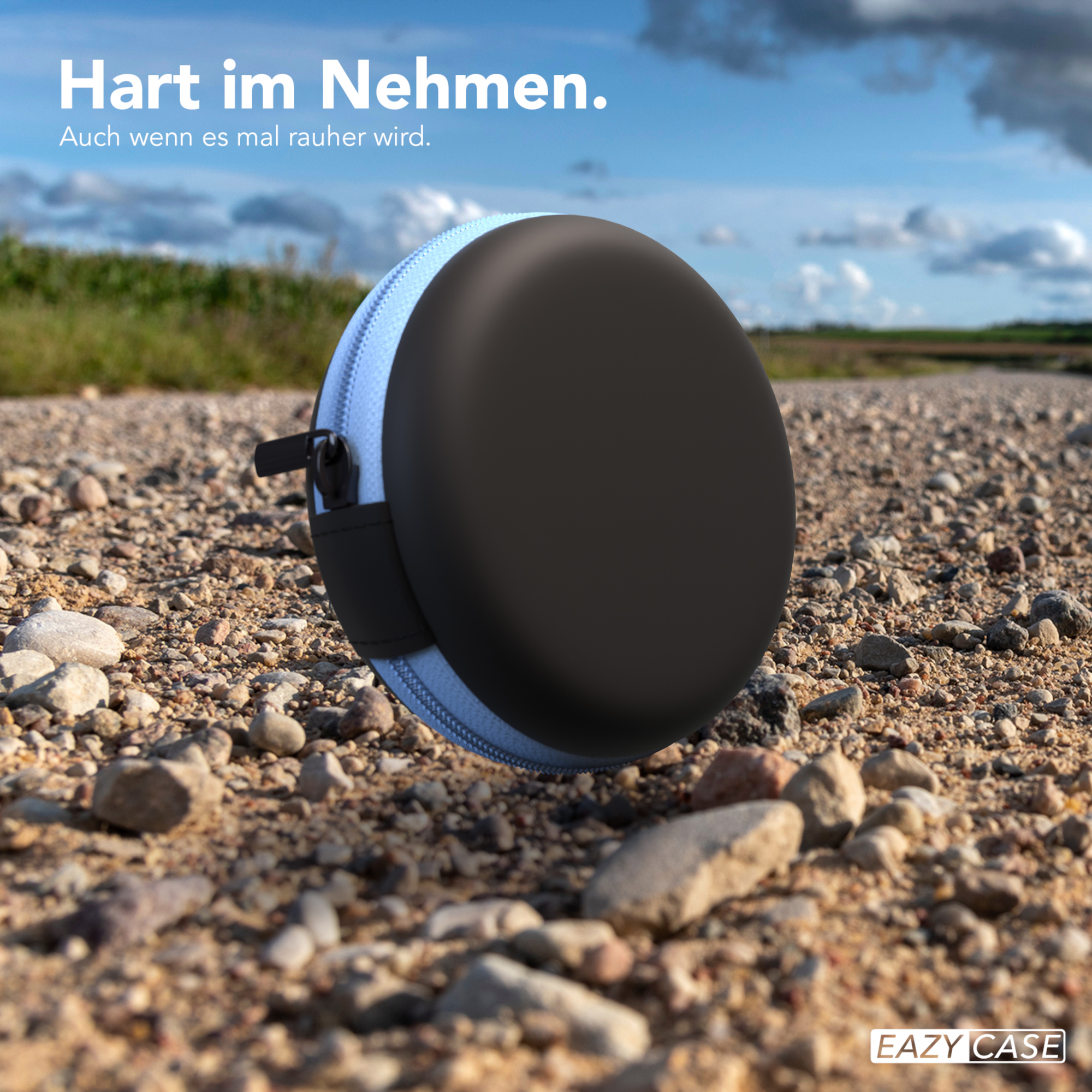 Ein schwarz-blaues Etui mit Reißverschluss liegt auf einem Kiesweg, mit dem Markennamen aufgedruckt.