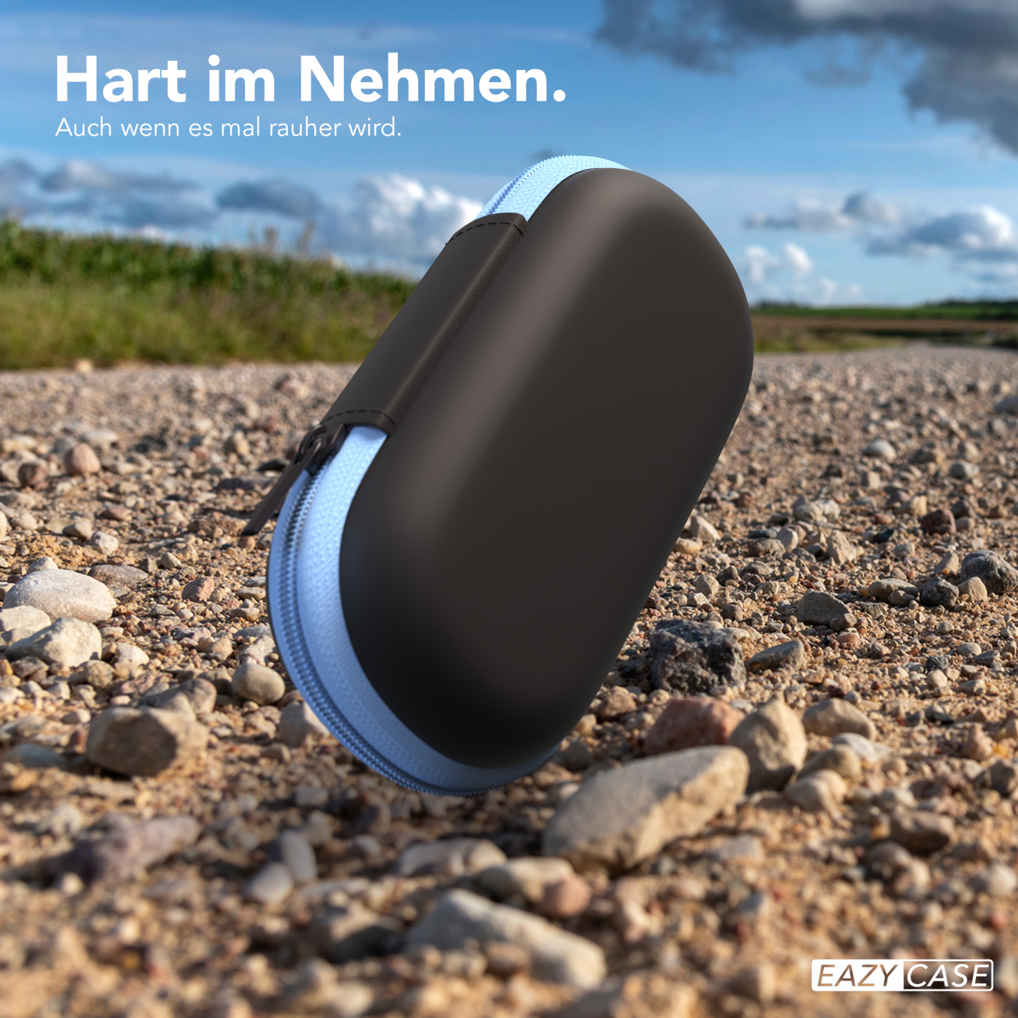 Schwarzes Etui mit blauem Reißverschluss auf einem Schotterweg, Haltbarkeit betonend.