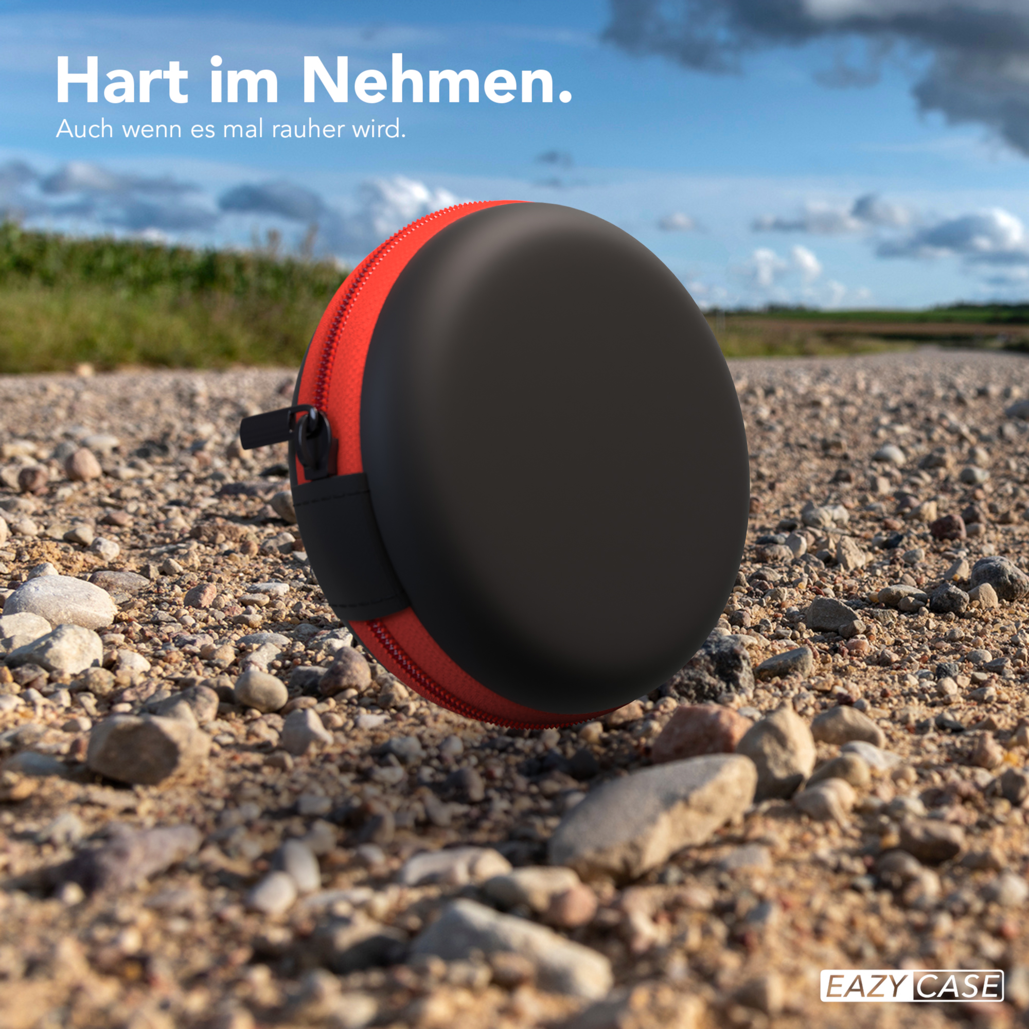 Eine schwarz-rote Kopfhörerhülle auf einer Schotterstraße, mit dem Text: Schwer zu nehmen. Auch wenn es rau wird.