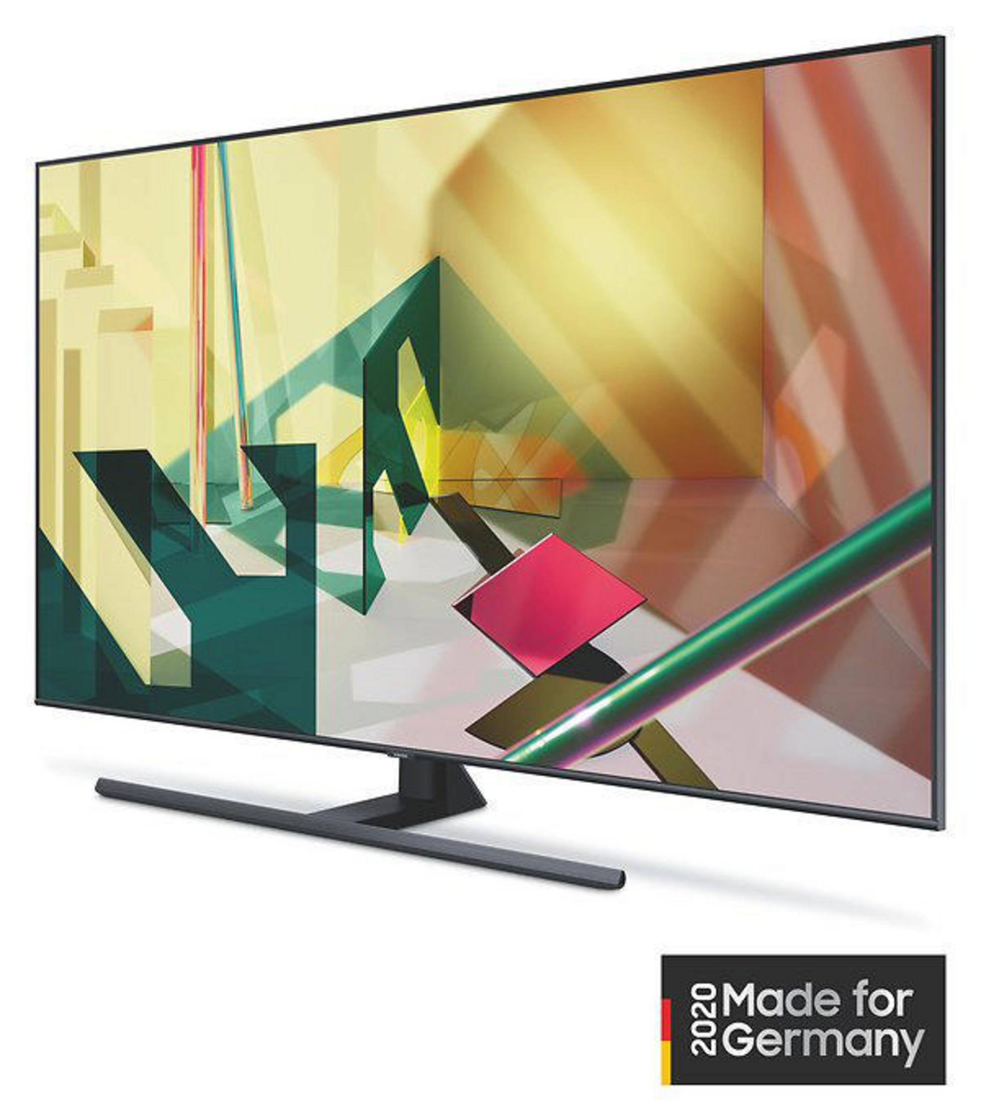Duży telewizor z abstrakcyjną sztuką geometryczną na ekranie, czarnym stojakiem i etykietą 'Made for Germany'.