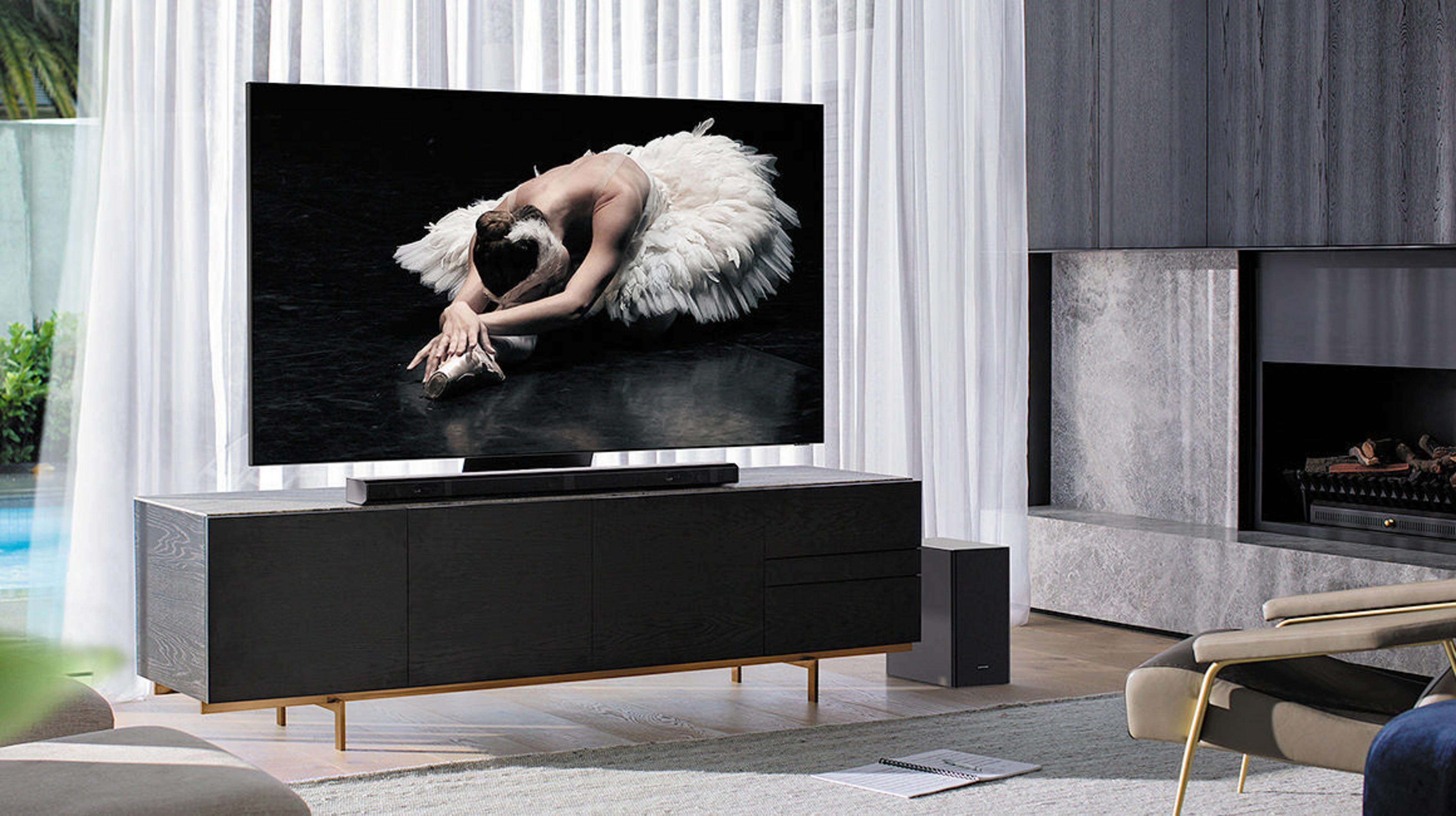 Ein Fernseher zeigt eine Ballerina. Eine Soundbar steht darunter. Im Hintergrund sind Kamin und Fenster.