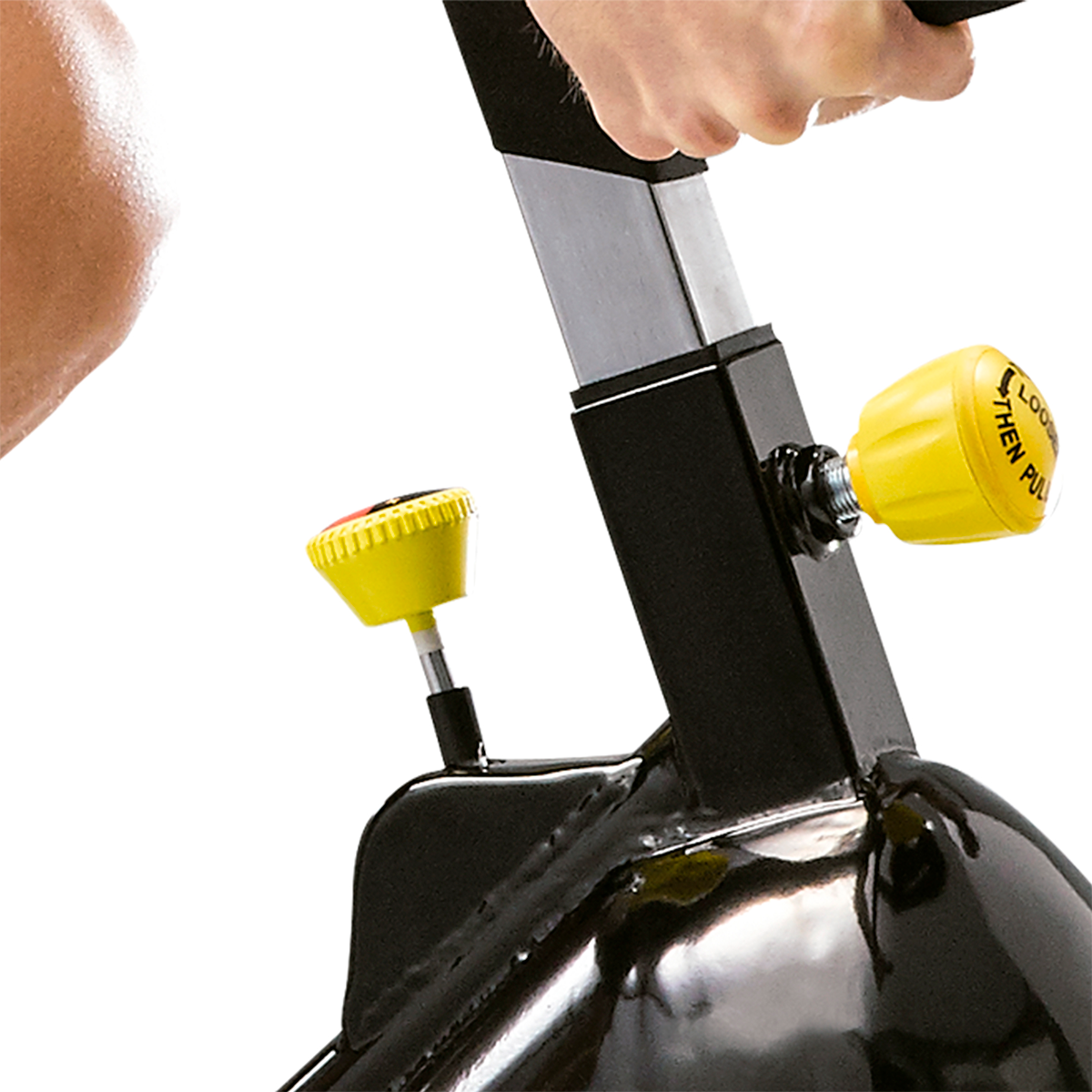 Primo piano di una manopola di regolazione gialla su una cyclette nera, sfondo bianco.