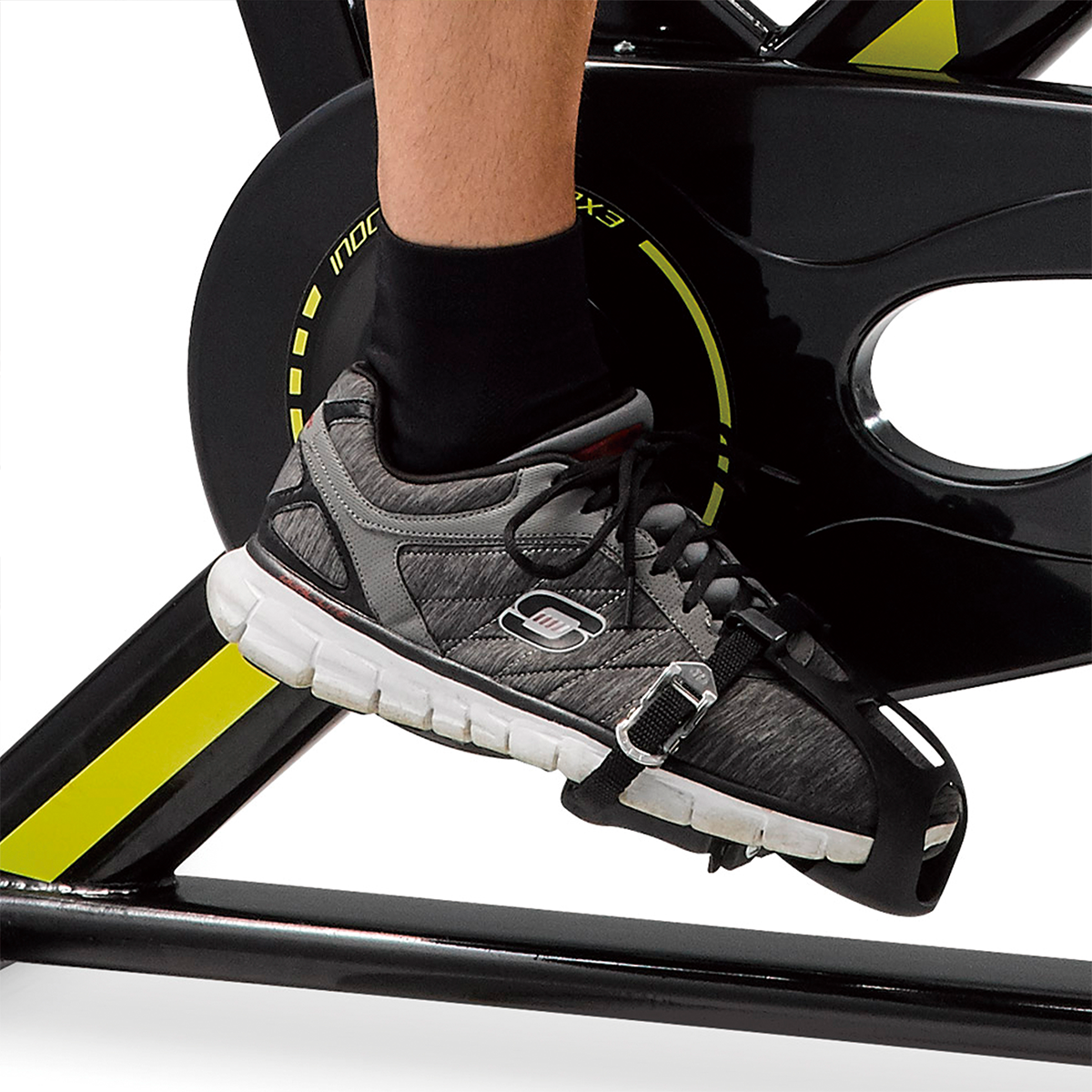Piede di una persona con una scarpa su una cyclette. Lo sfondo è bianco.