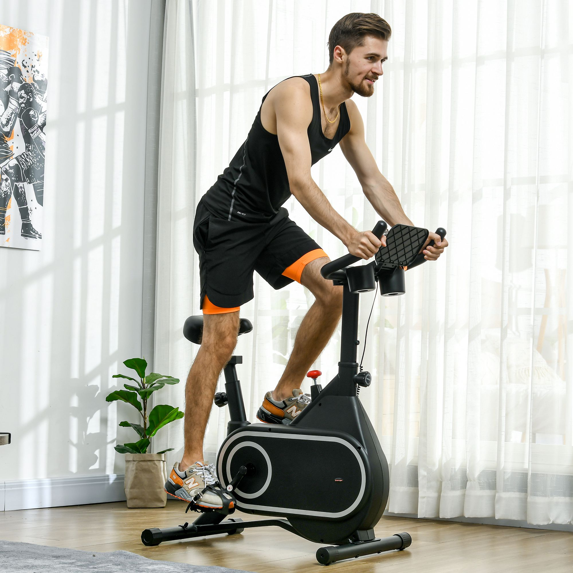 Un uomo su una cyclette. Indossa pantaloncini neri, canotta e scarpe da ginnastica arancioni. Sfondo: tende bianche.