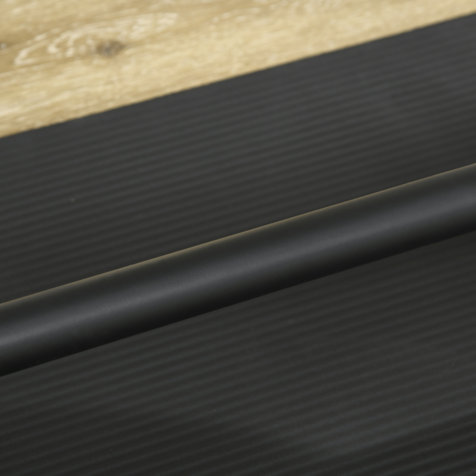 Primer plano de una barra negra sobre una superficie texturizada negra con borde de madera.