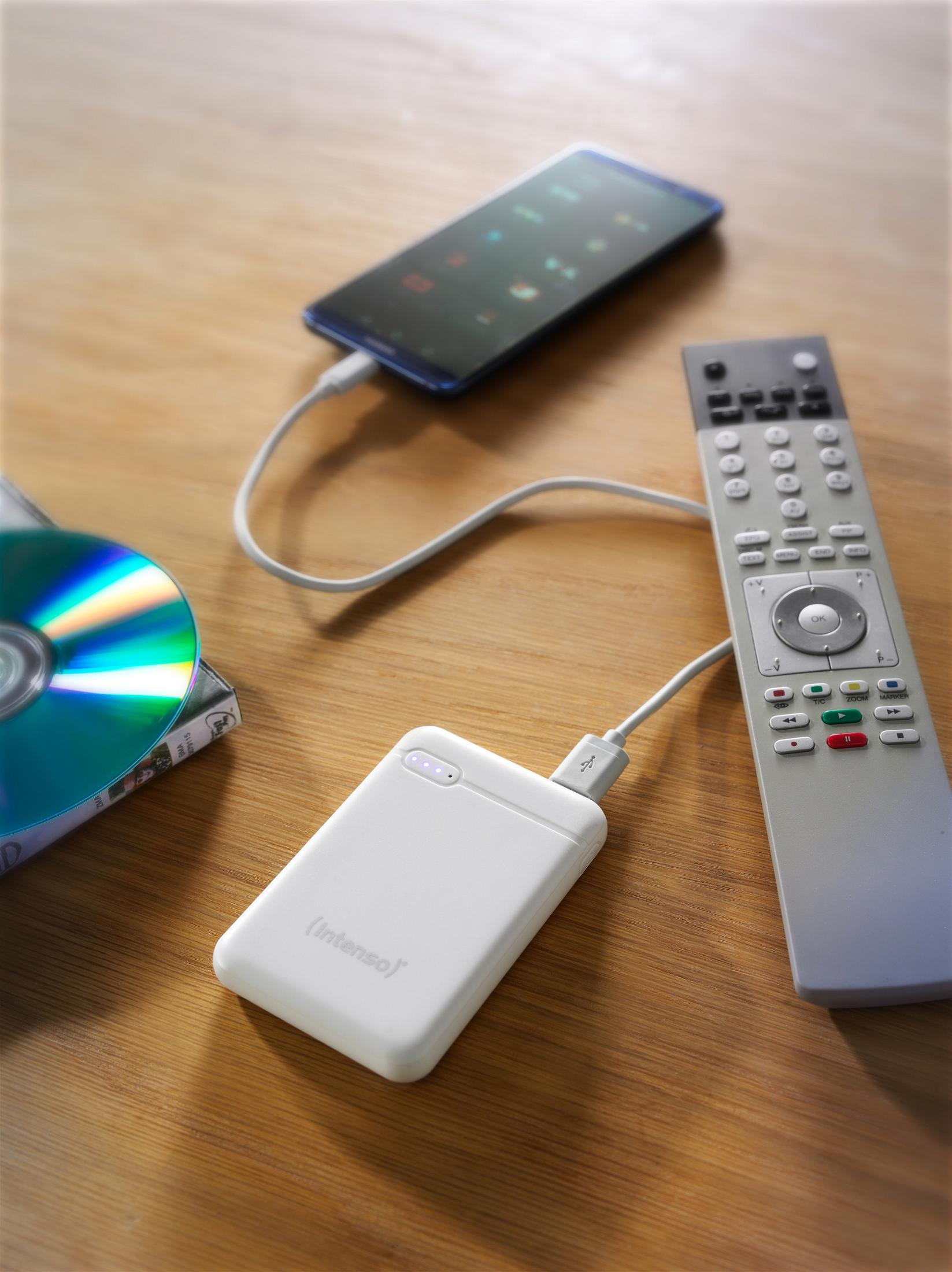 Een witte powerbank aangesloten op een zwarte smartphone met een oplaadkabel op een houten tafel.