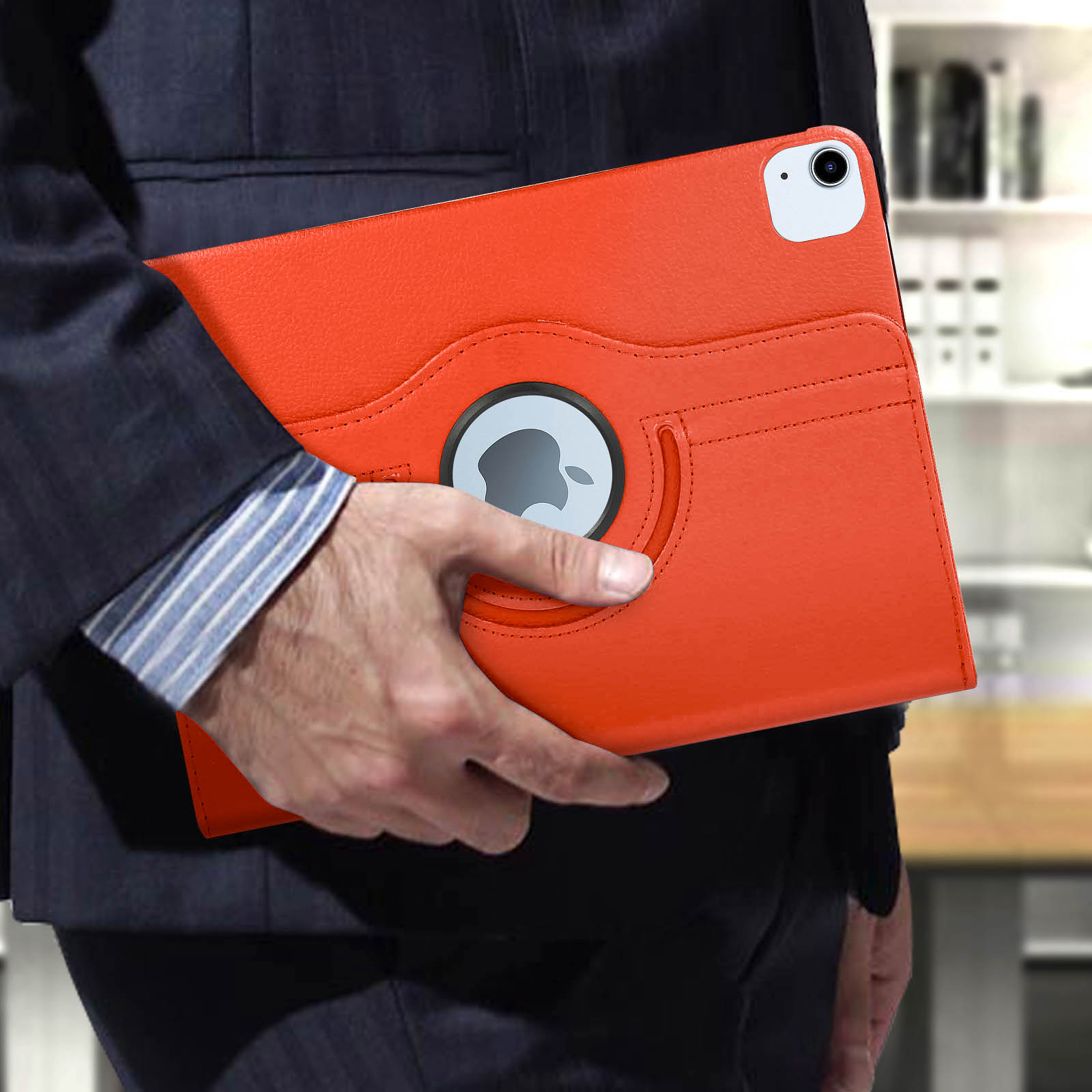 Una persona tiene un iPad arancione in una custodia. Il logo Apple è visibile.