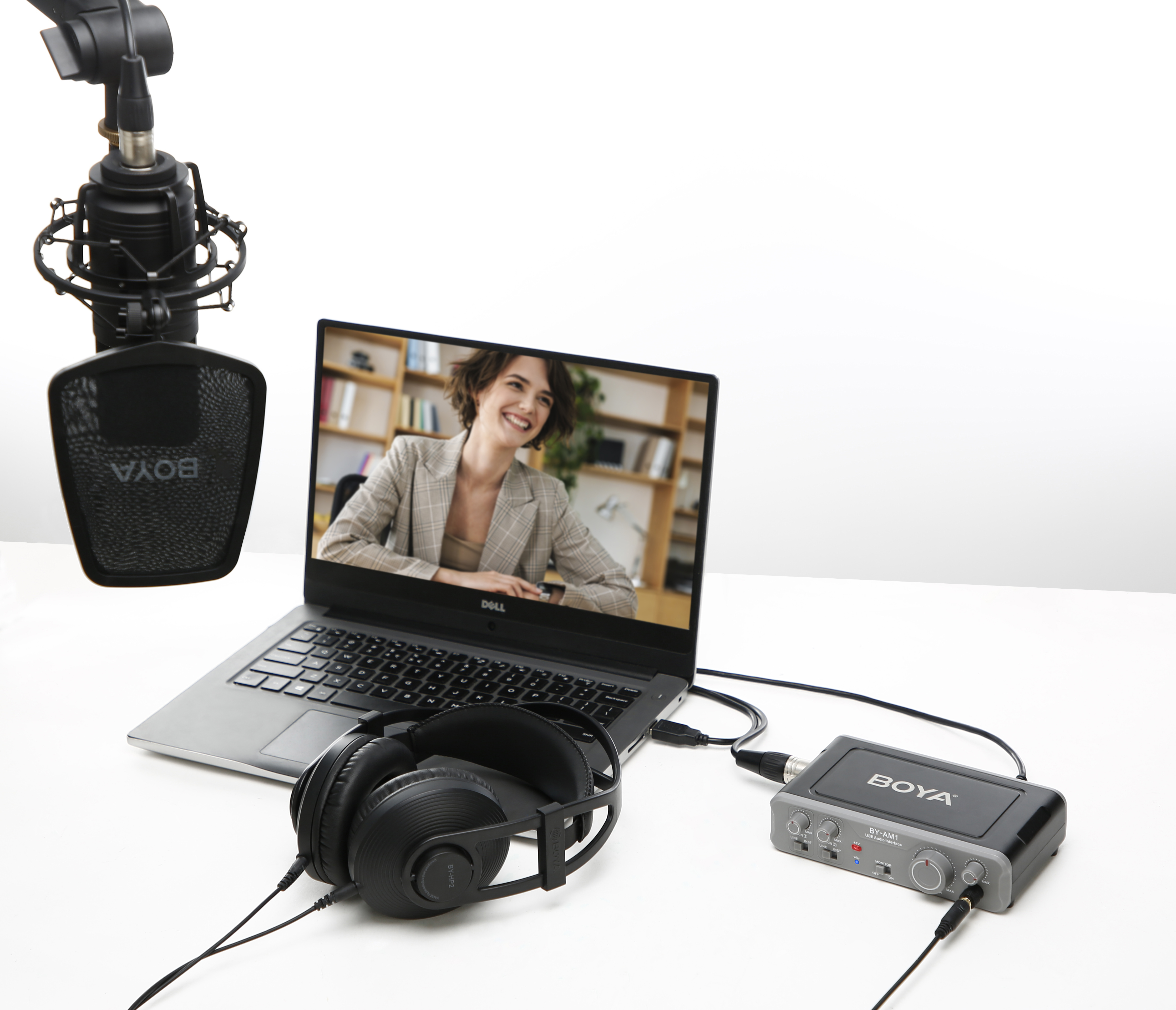 Ordenador portátil con videollamada, micrófono, auriculares e interfaz de audio sobre superficie blanca.